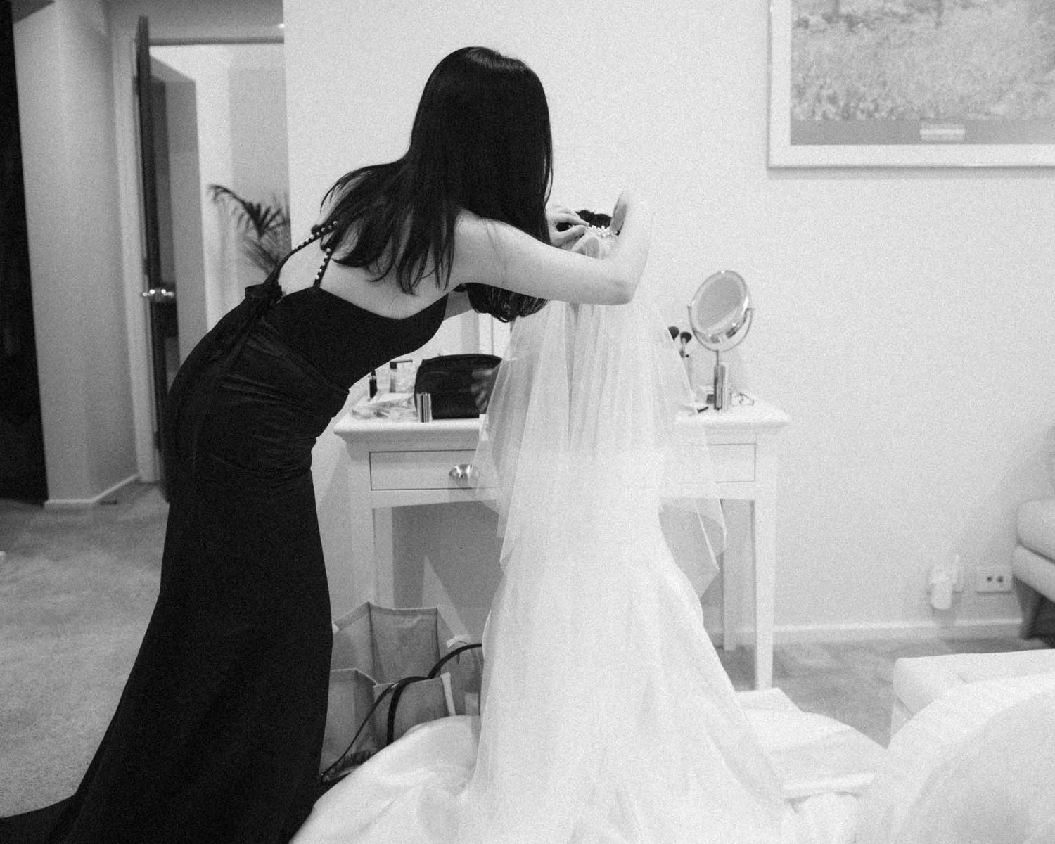 Bridesmaid helps bride put in her veil while wearing her wedding dress for a Barossa Valley wedding captured by Matt Webster.
