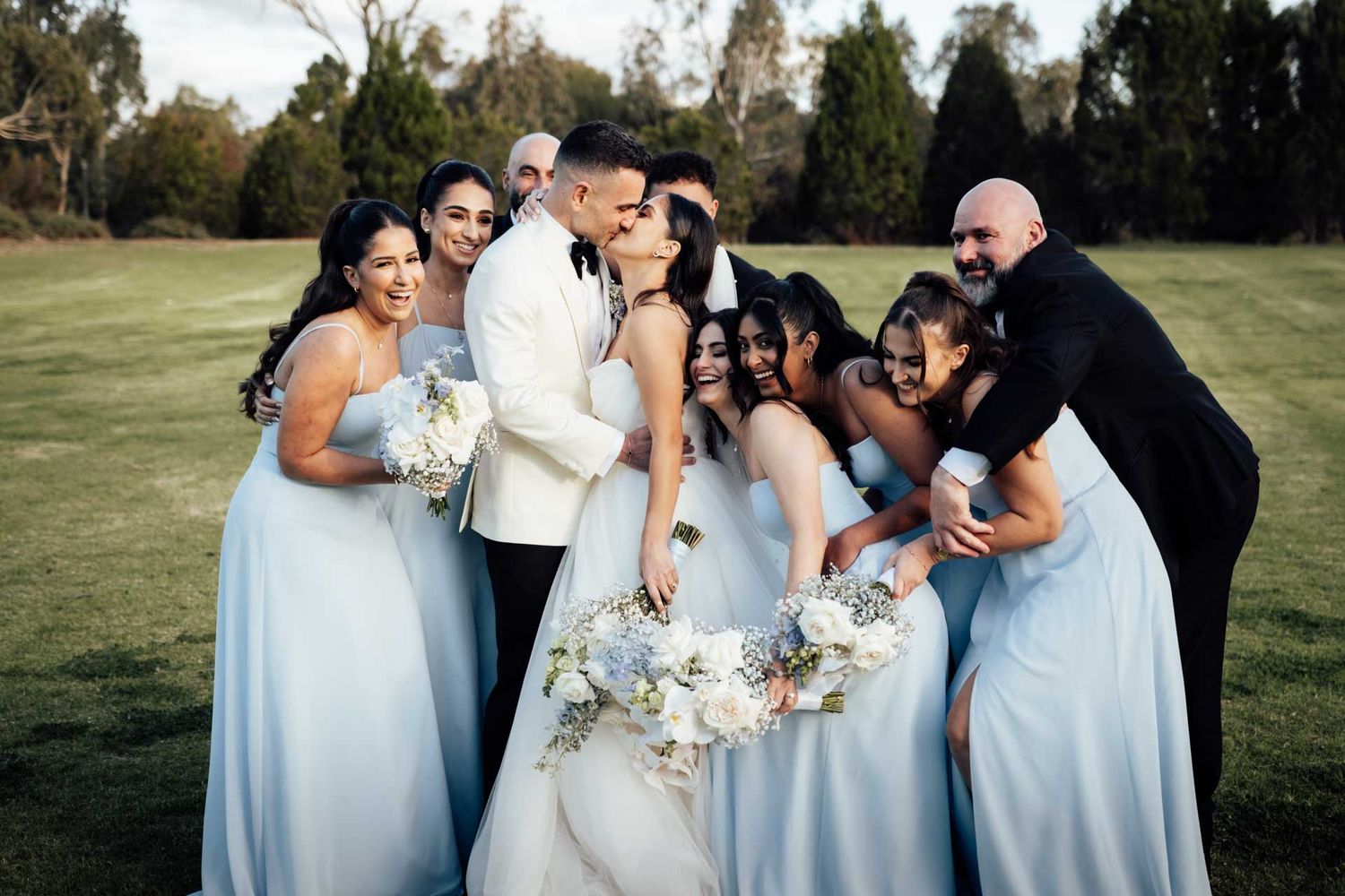 Bridal party hug the bride and groom at Sunnybrae Estate during a wedding reception, photographed by Matt Webster.