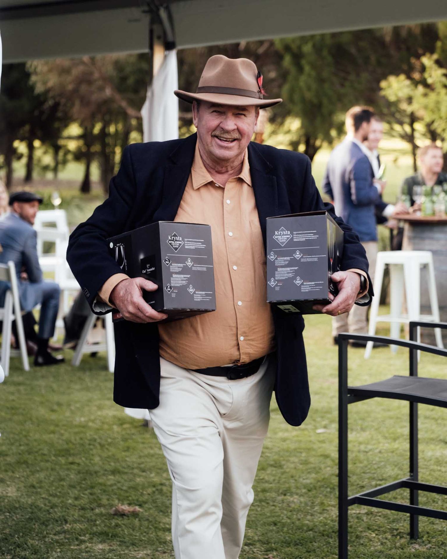 Guest carrying boxes of wine at outdoor wedding in Tanunda captured by Barossa Valley photographer Matt Webster
