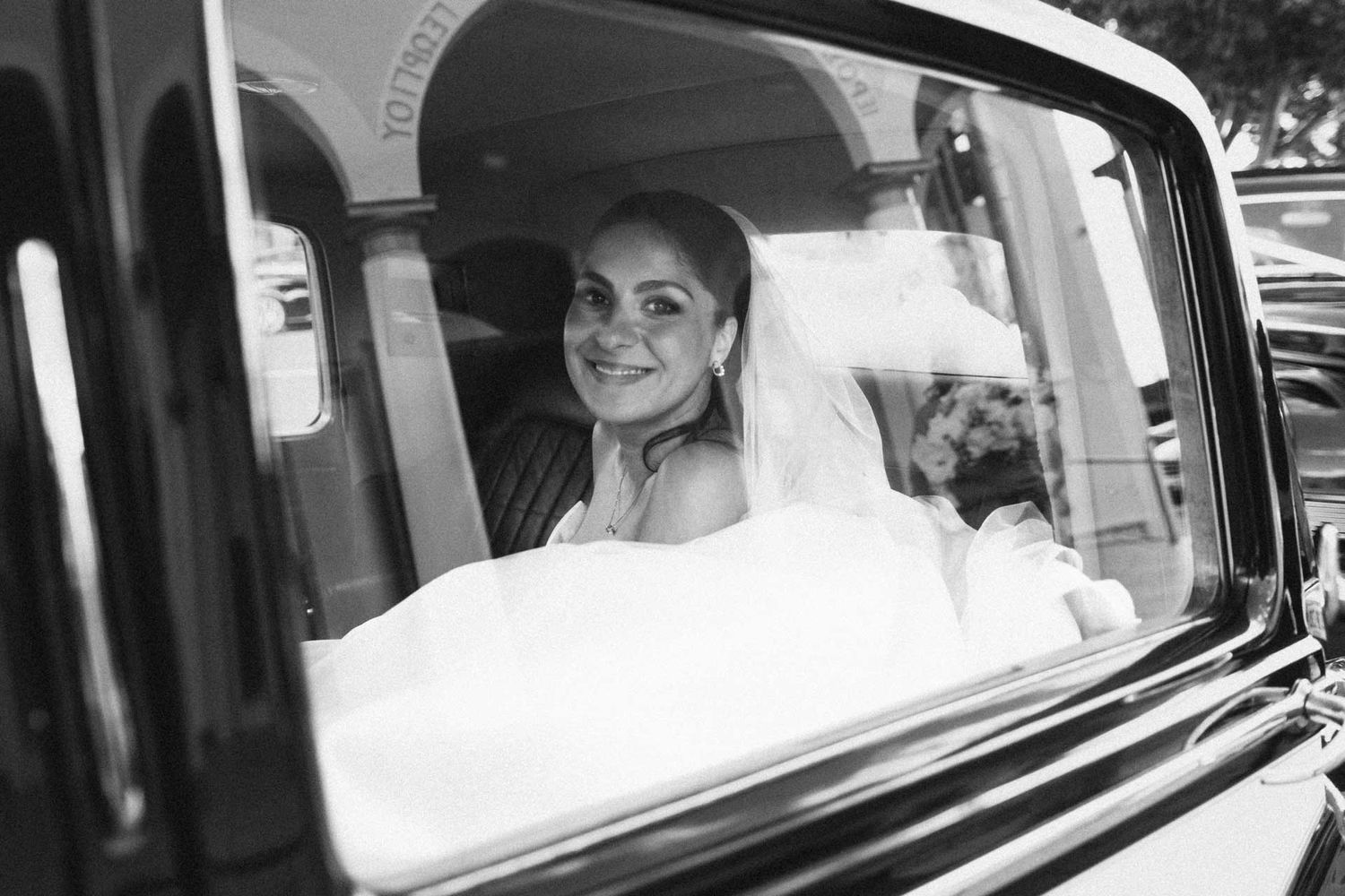 Bride smiling through the window of a Bentley at St George Orthodox Church, Thebarton, captured by Matt Webster.