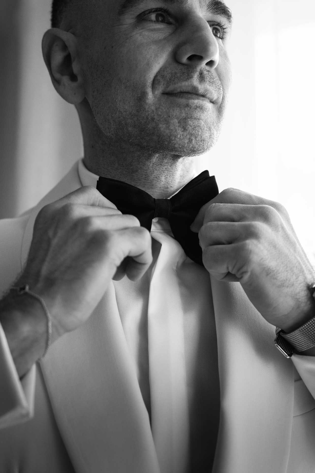 Black and white portrait of groom fixing his bowtie in black and white, captured by Barossa Valley photographer Matt Webster.