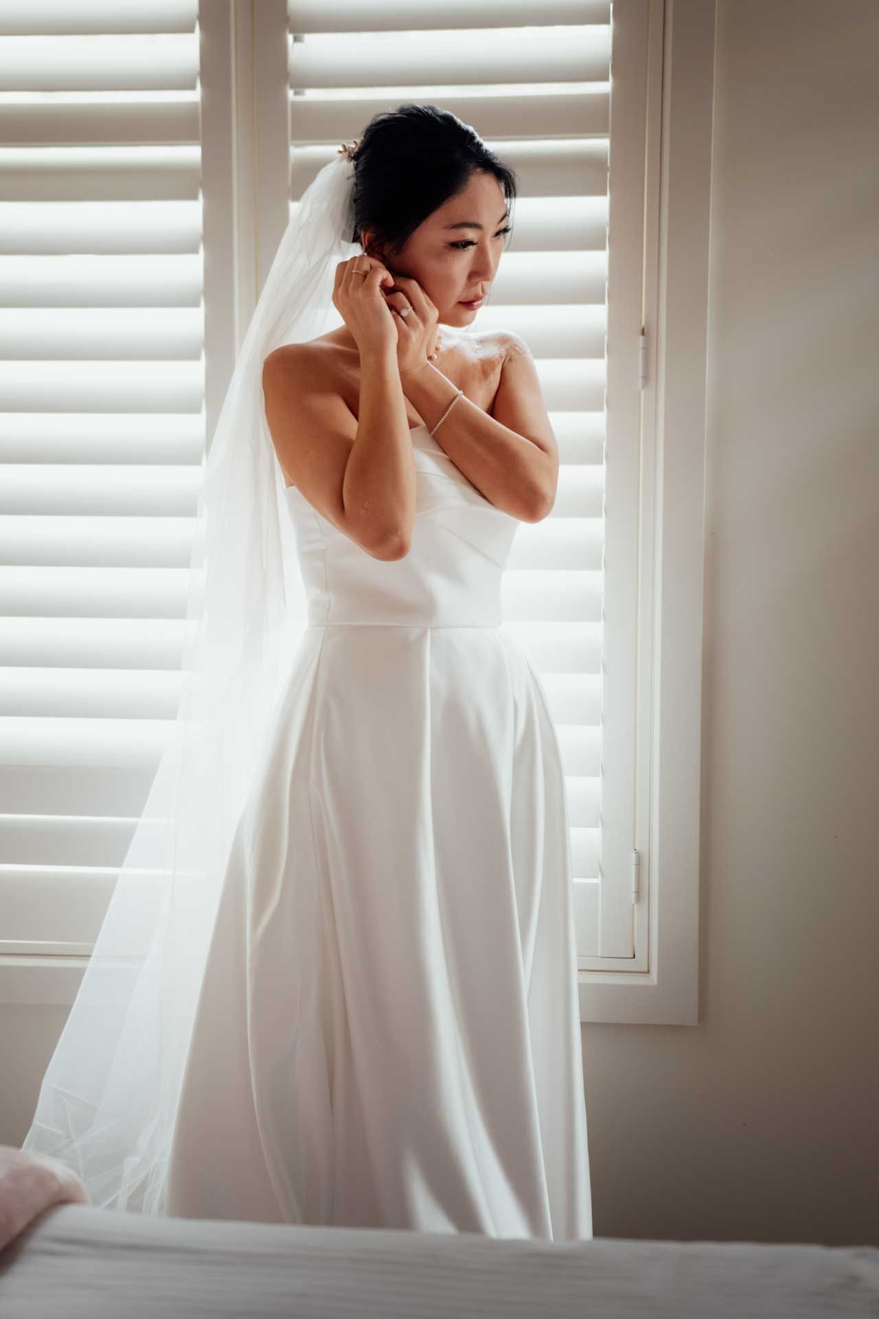 Bride wearing her wedding dress putting her earrings in during a Barossa Valley wedding captured by Matt Webster.