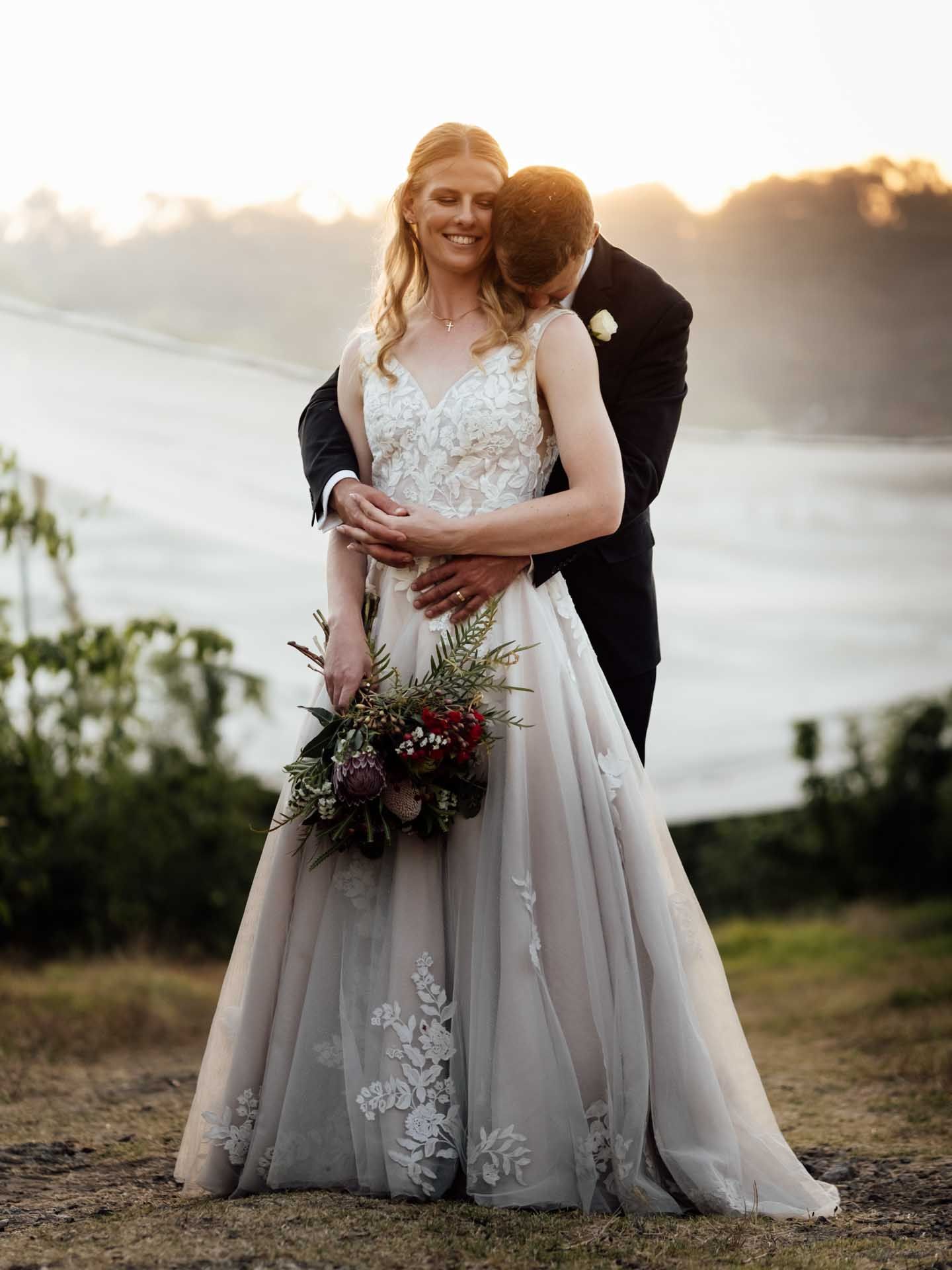 Groom kisses his brides neck during sunset photos in the Adelaide Hills, photographed by Barossa Valley wedding photographer Matt Webster.