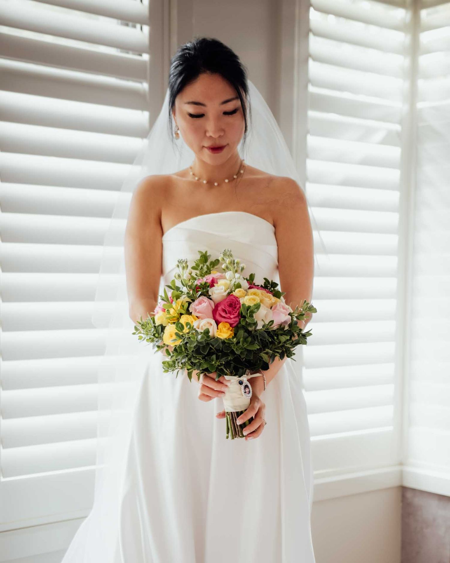 Bride wearing her wedding dress looks at her bouquet while getting ready for her Barossa Valley wedding captured by Matt Webster.
