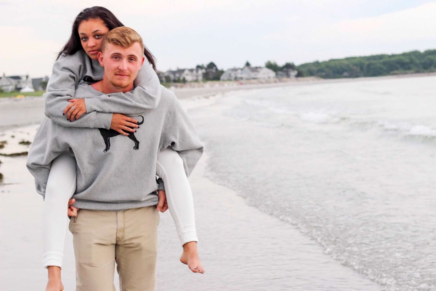 Playful beach photoshoot with couple enjoying piggyback rides near the water.