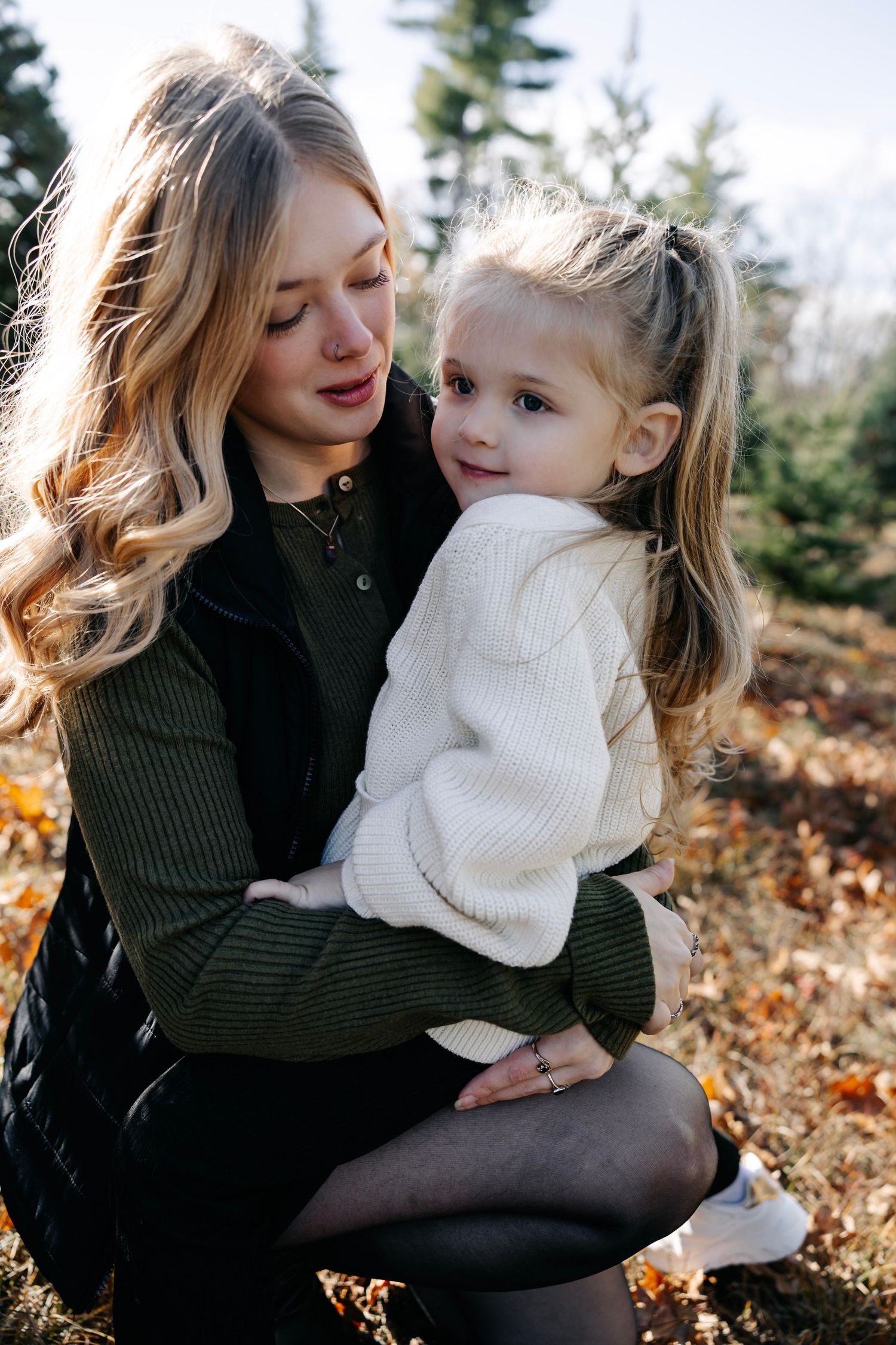 Intimate family portrait session among evergreen trees at Christmas tree farm.