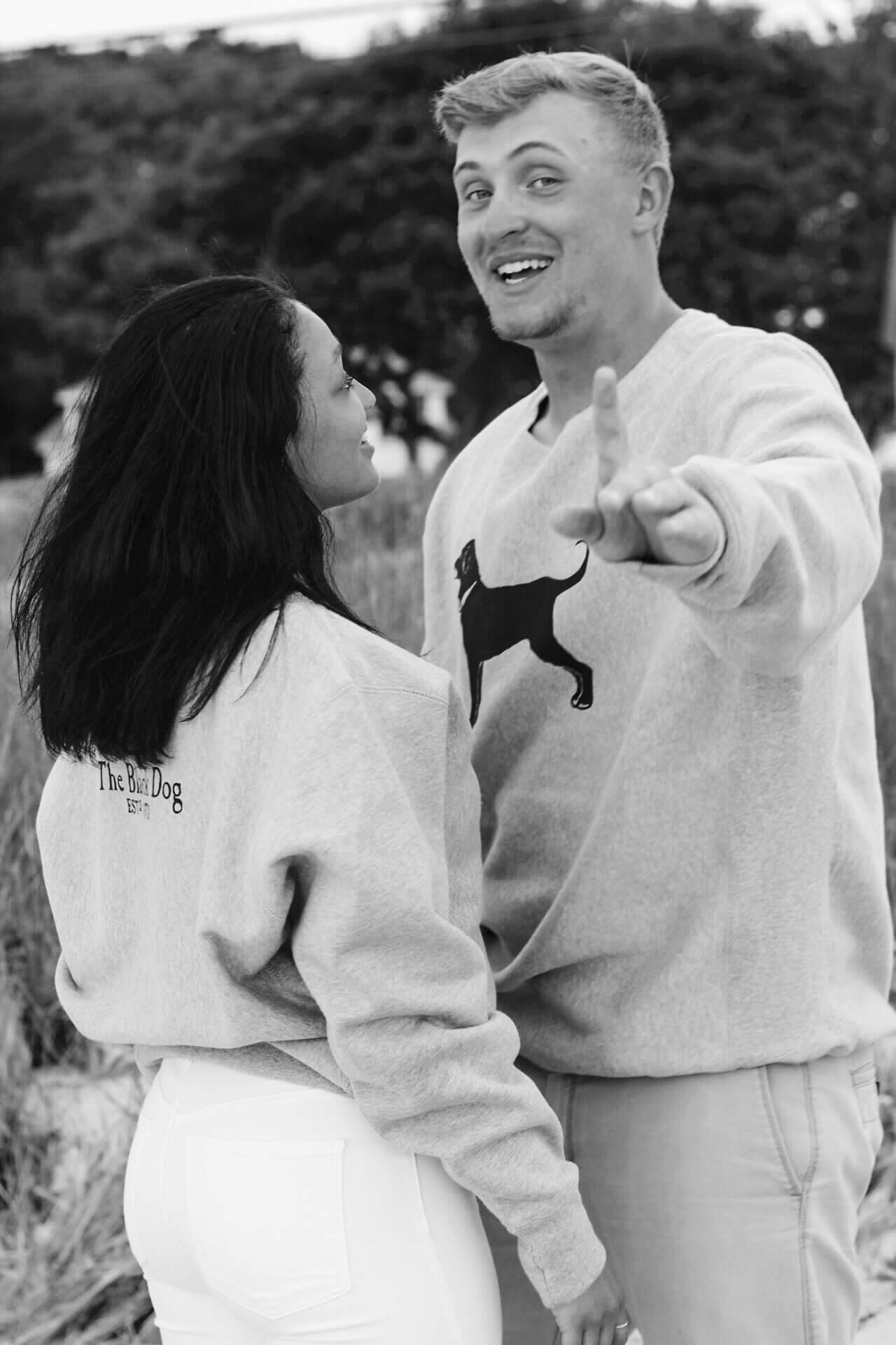 Candid black and white photos of a laughing couple in matching sweatshirts.