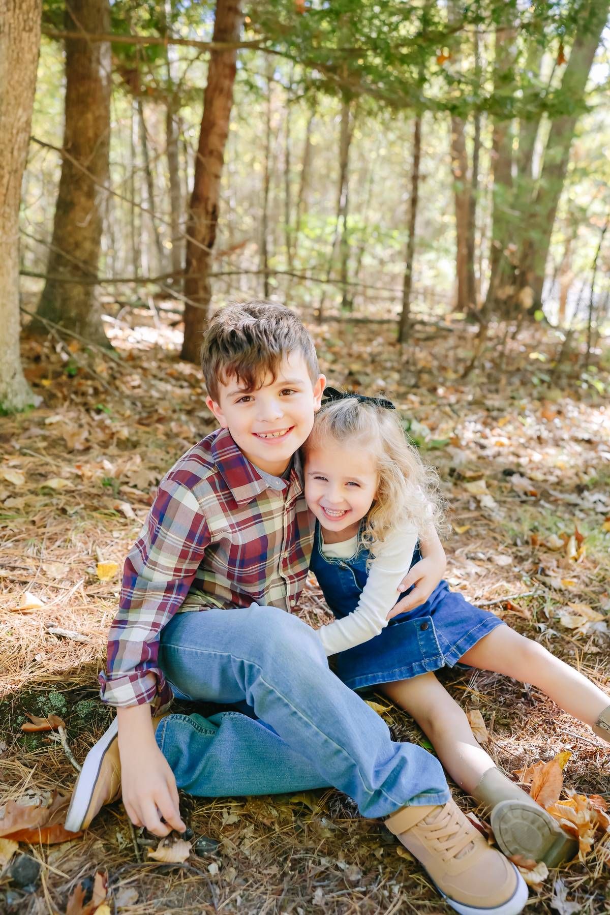Playful autumn photoshoot on fallen leaves in a wooded setting.