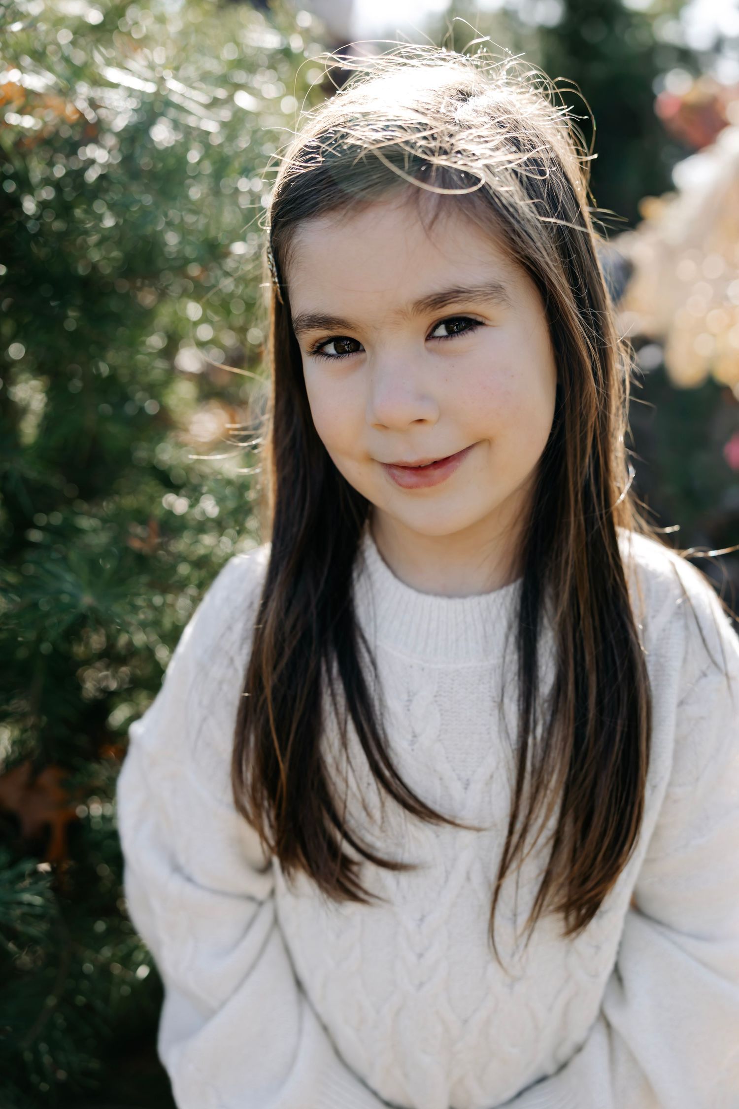 Close-up portrait showing warm smile while wearing a cozy white sweater outdoors.