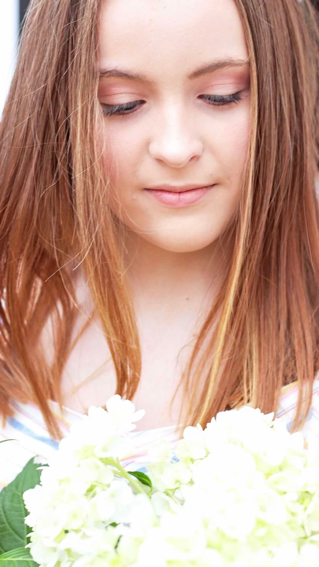 Close-up view of person with long hair looking down at white flowers.