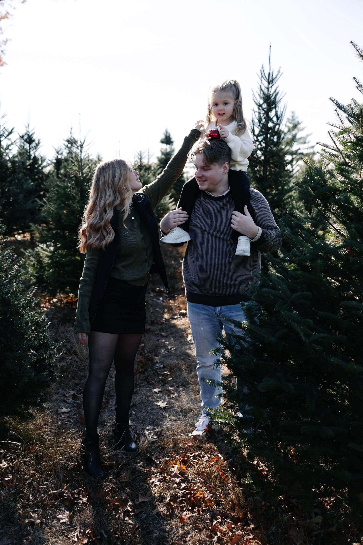Casual family moment captured while walking through Christmas tree farm in autumn.