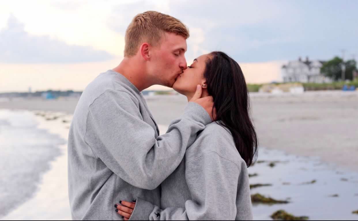 Romantic couple sharing tender moments during a beach photoshoot.
