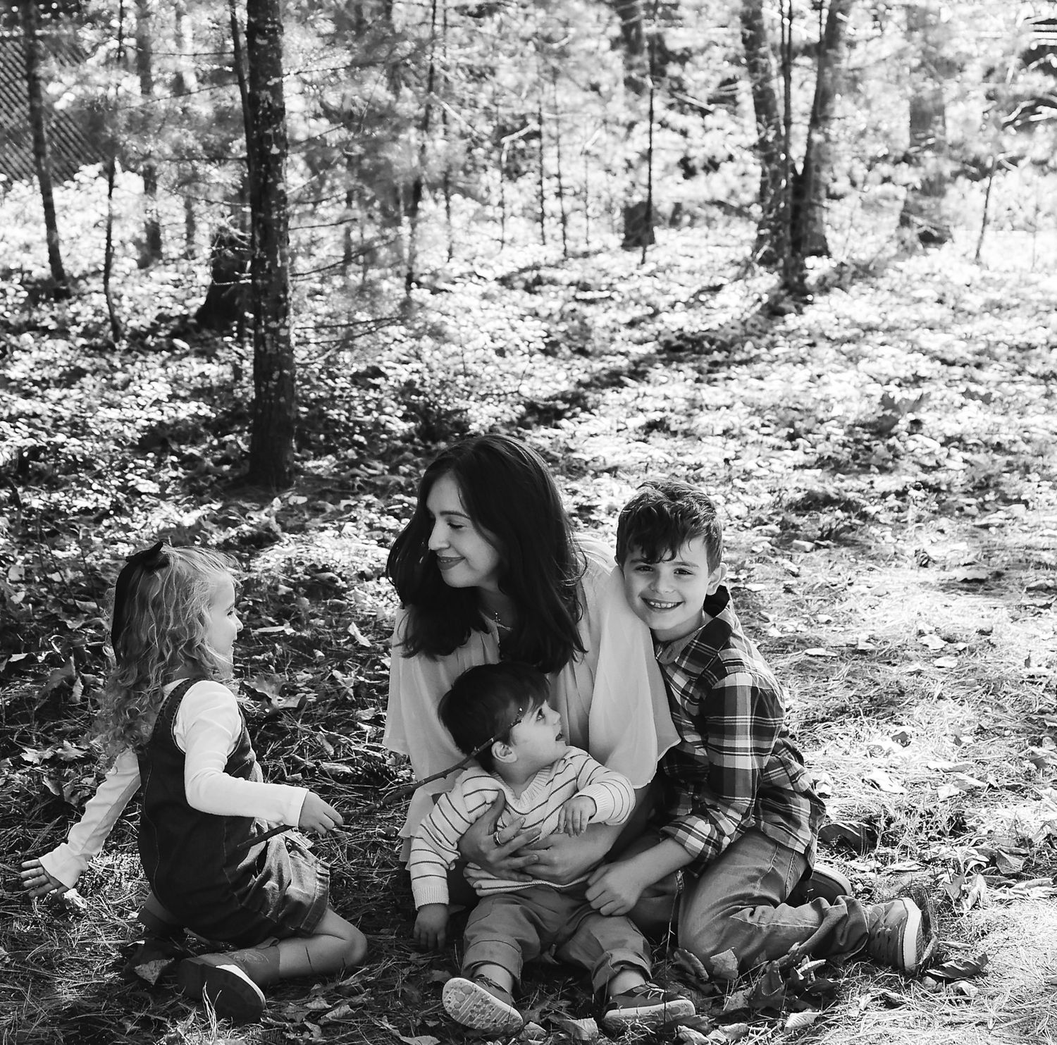 Black and white photograph of a family relaxing together in a forest setting.
