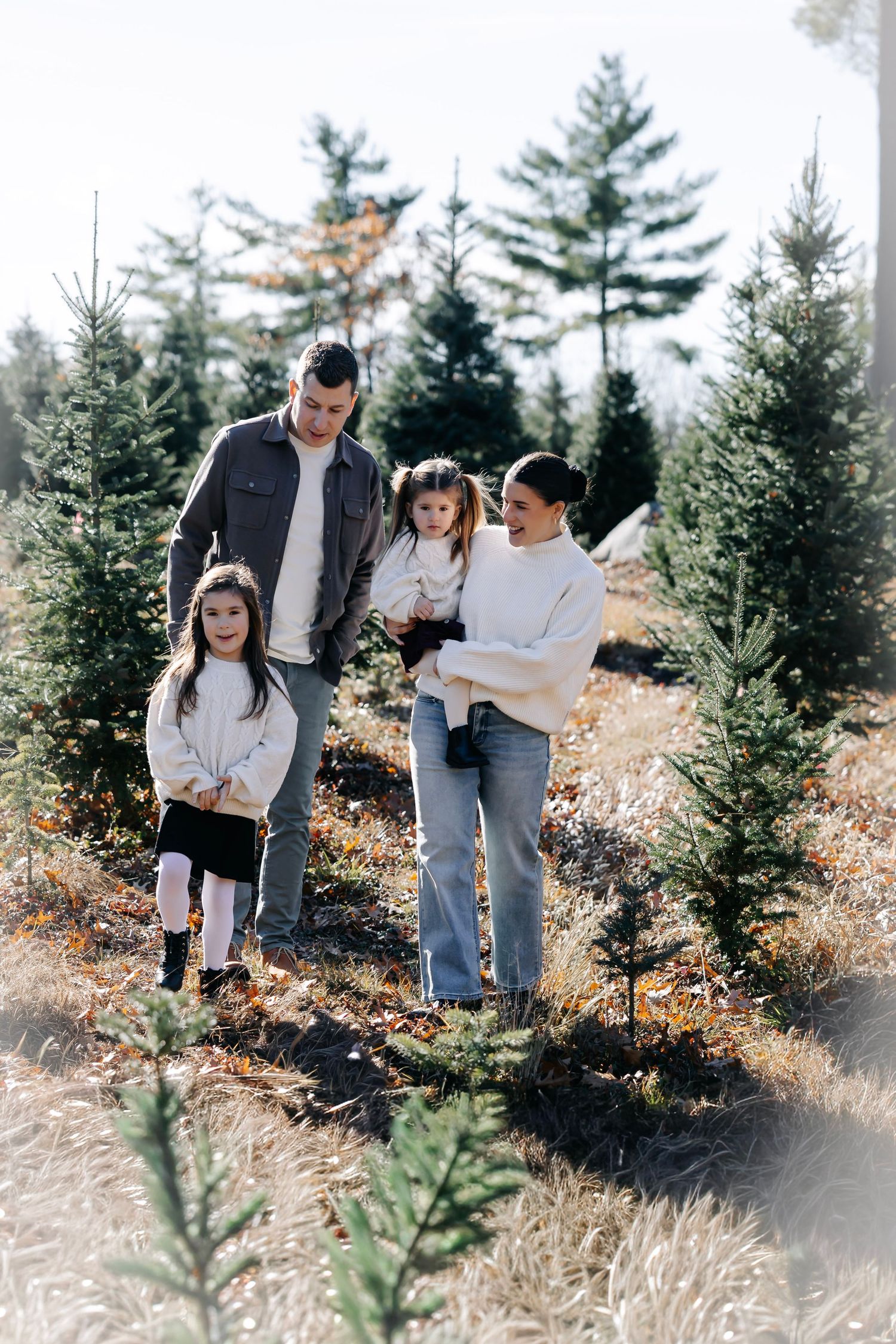 Family enjoying a sunny autumn day together while walking through a Christmas tree farm.