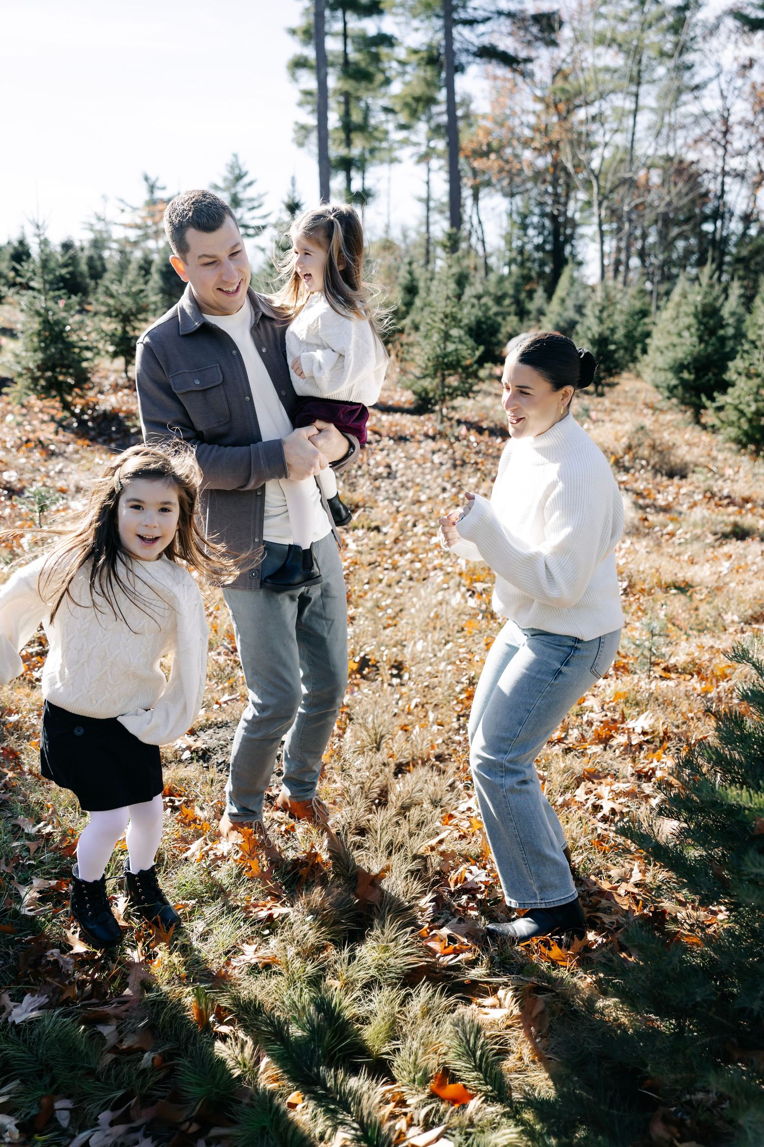 Playful family moments captured in motion among fallen leaves and evergreen trees.