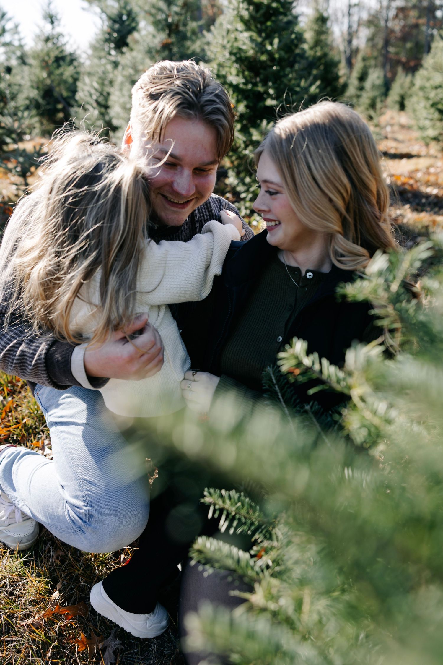 Romantic moment captured between couple among evergreen trees during outdoor photoshoot.