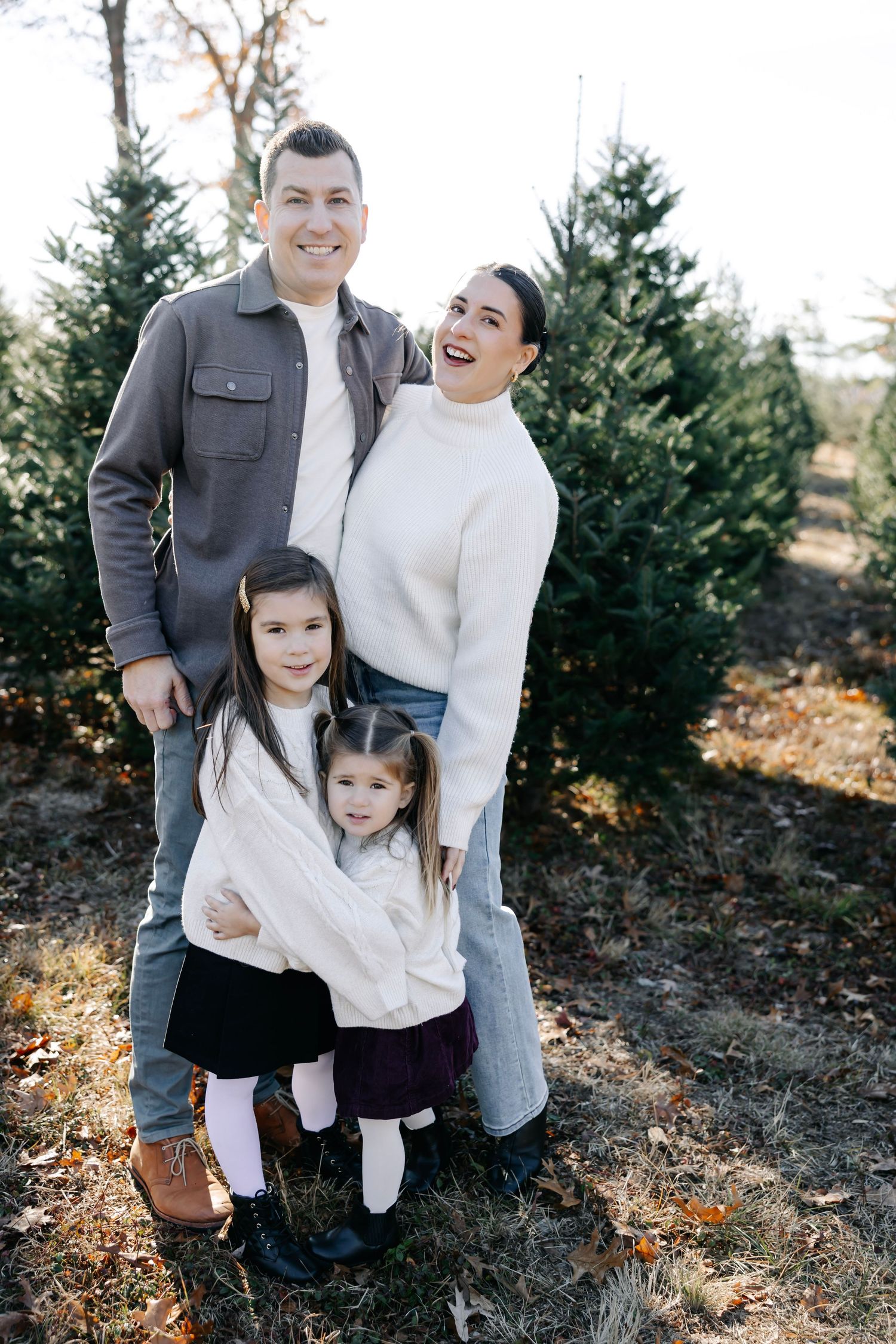 A joyful family photoshoot in nature with everyone wearing coordinated winter outfits.