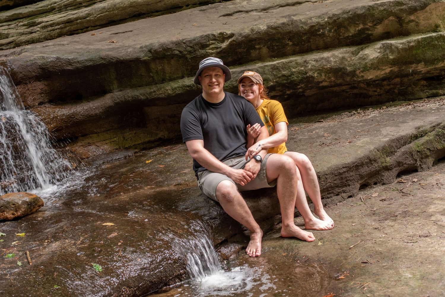 A couple lovingly sitting together in front of a waterfall in Matthiesen Park
