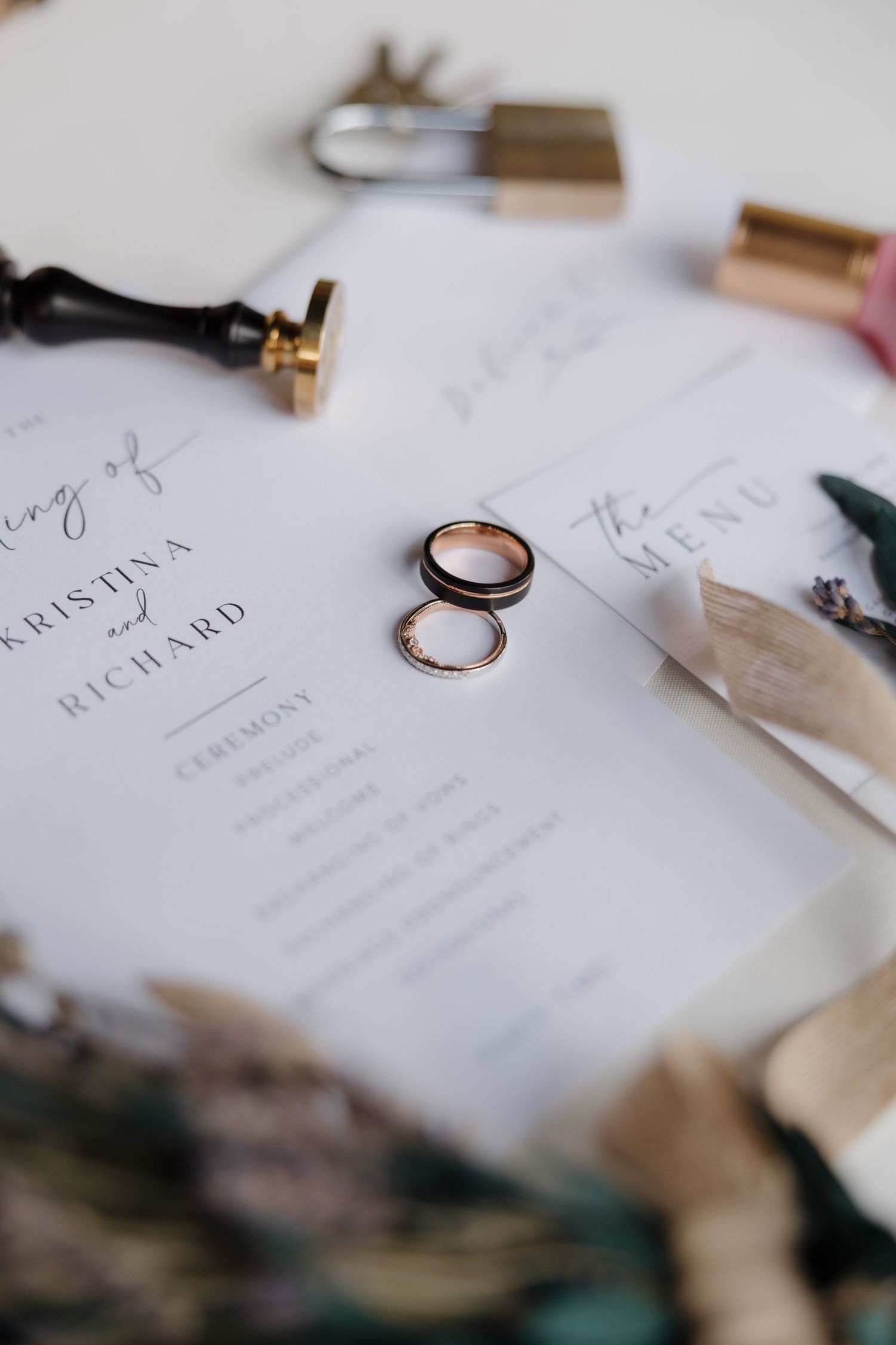 Wedding invitation cards and rings arranged on a white surface in an elegant flat lay composition.