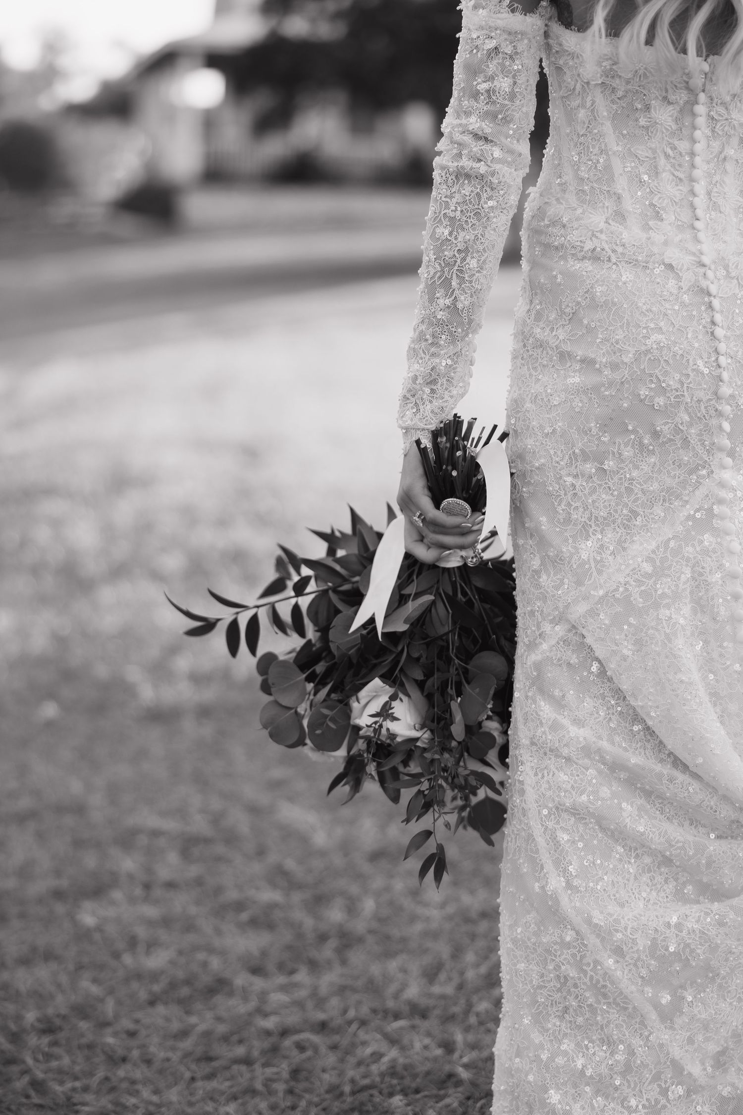Black and white close-up photograph of plants growing against a textured stone wall or column.