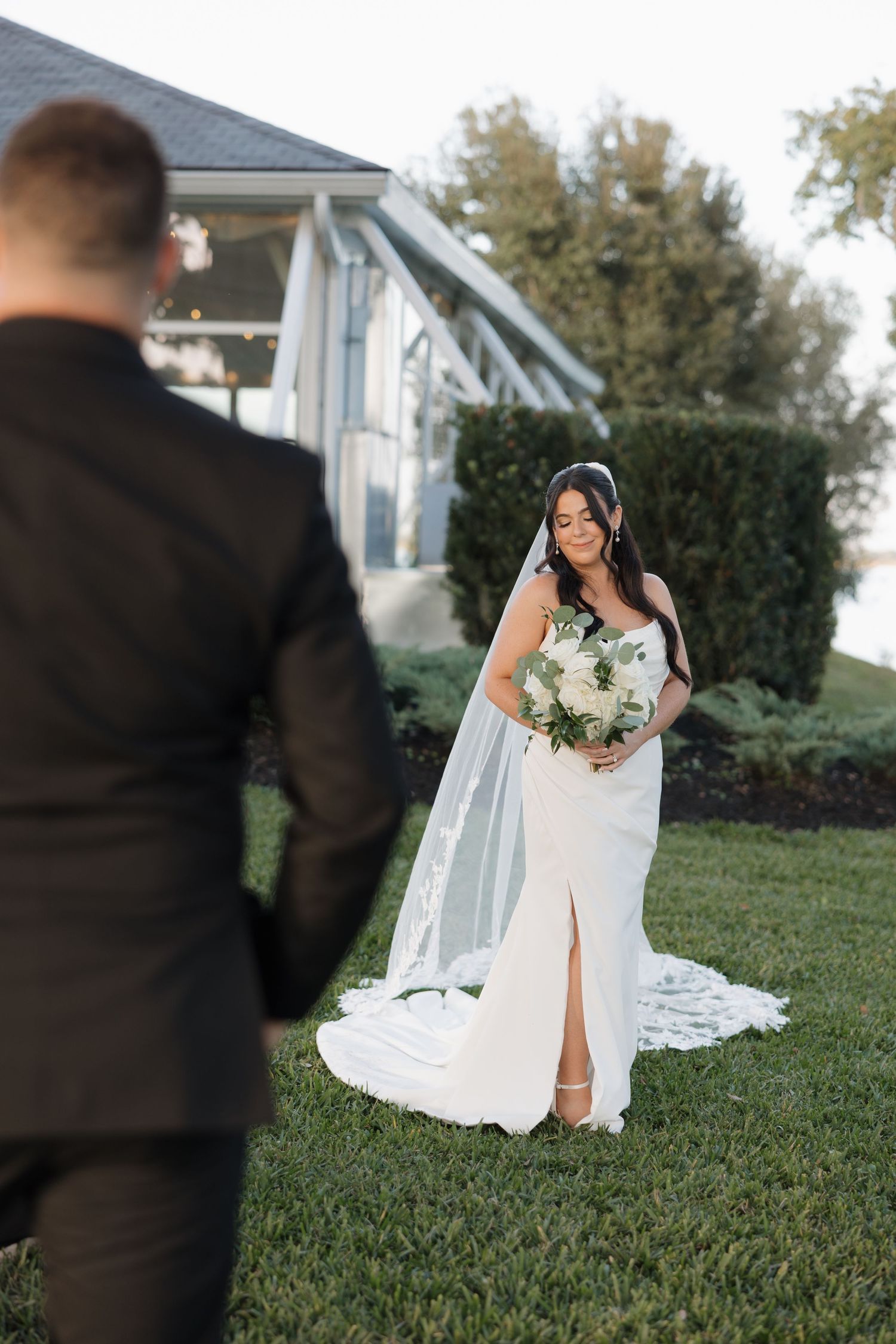 Wedding scene on manicured lawn with white dress and veil in motion.