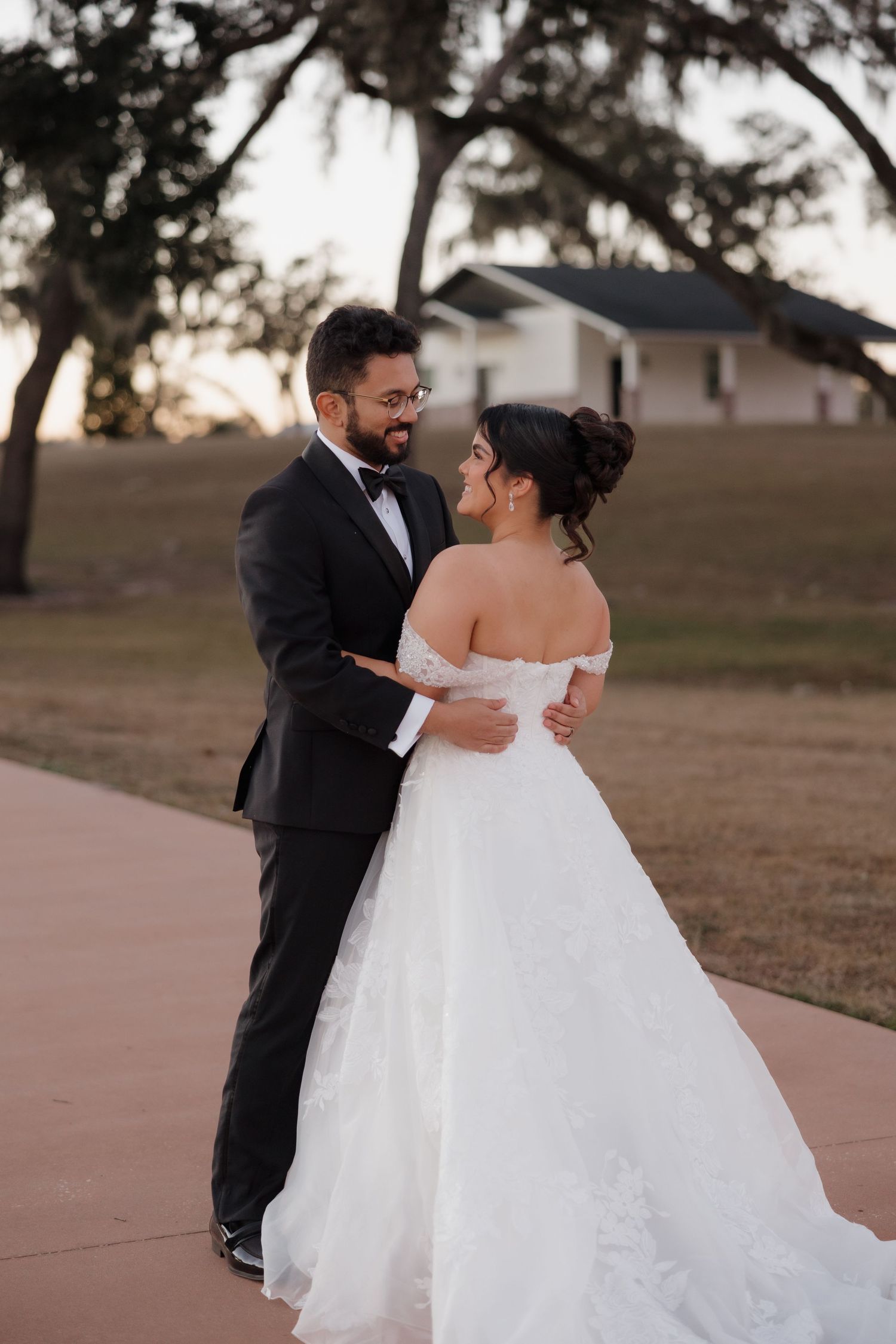 A romantic first dance moment between newlyweds at an outdoor wedding venue during sunset.