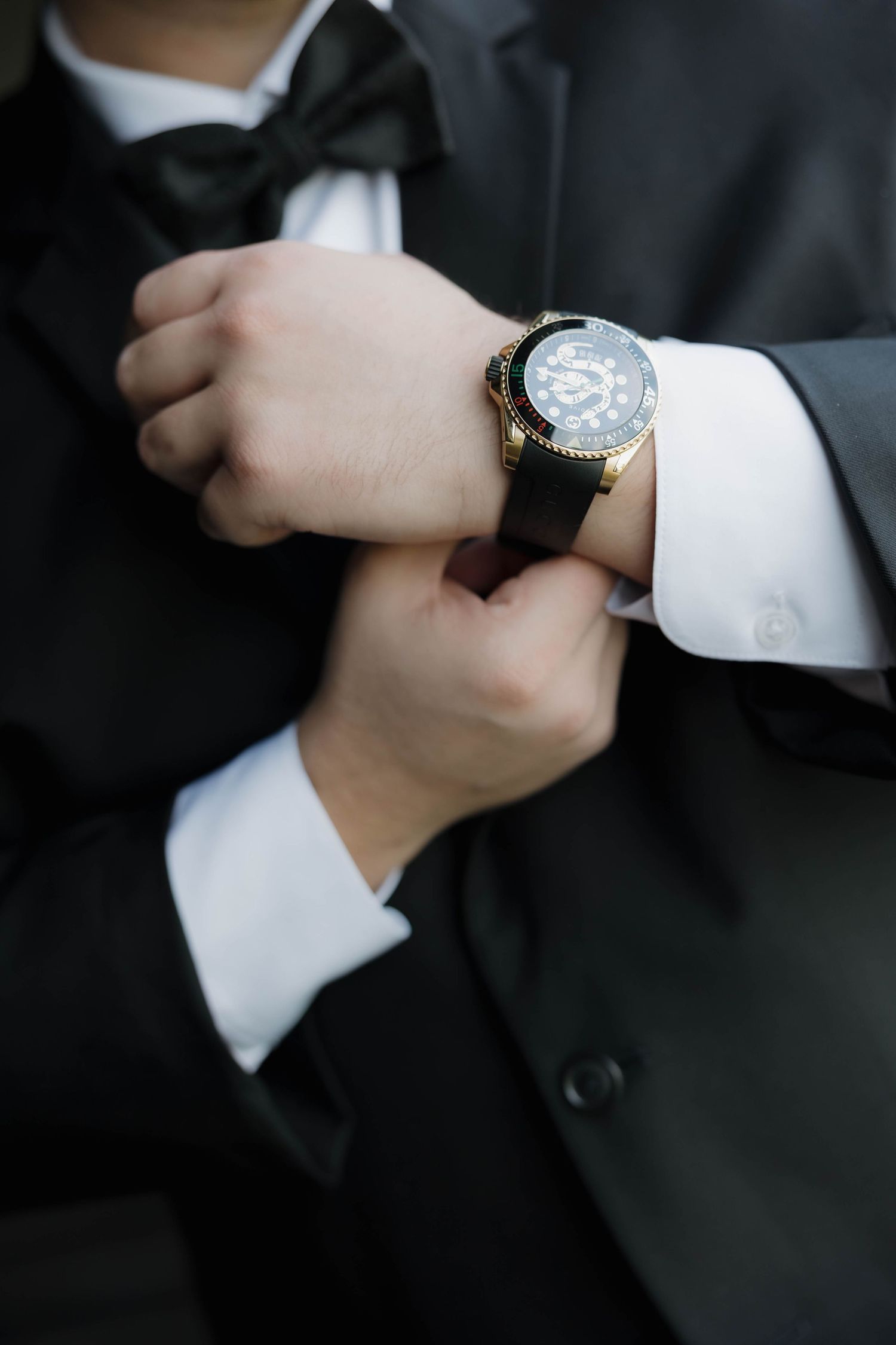 Close-up shots of hands adjusting a wristwatch while wearing a formal black suit and white dress shirt.