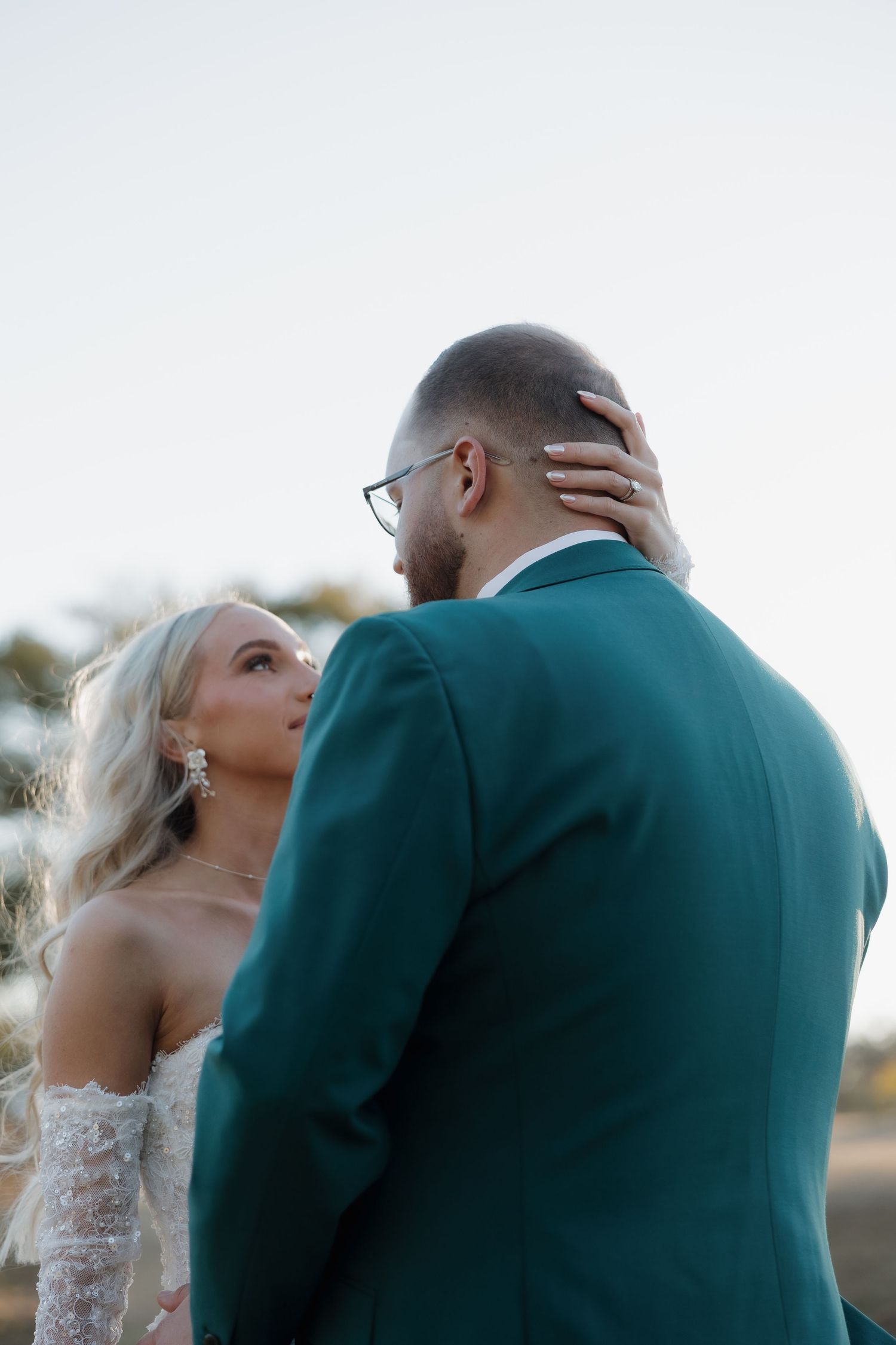 Newlywed couple sharing intimate kisses during outdoor wedding photoshoot at golden hour.