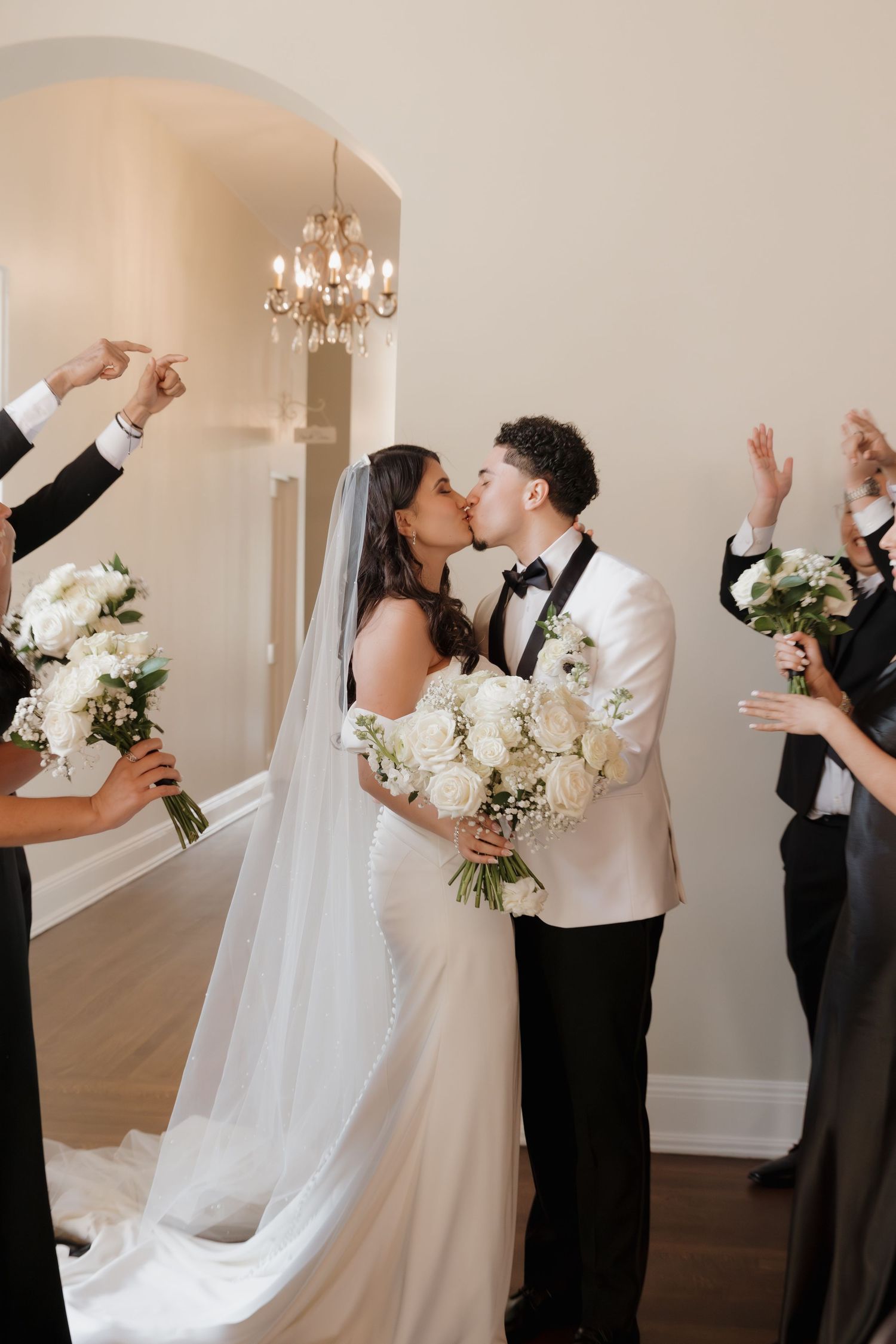 A romantic wedding sequence showing the couple sharing their first kiss in an elegant indoor venue with a chandelier.