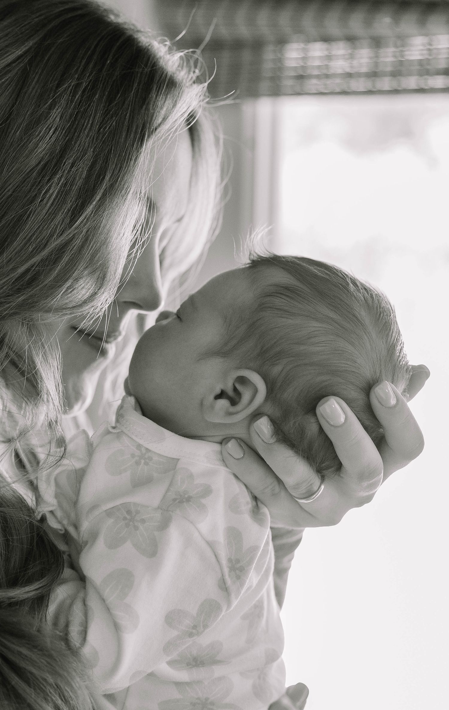 A tender black and white portrait of a parent holding a newborn baby.