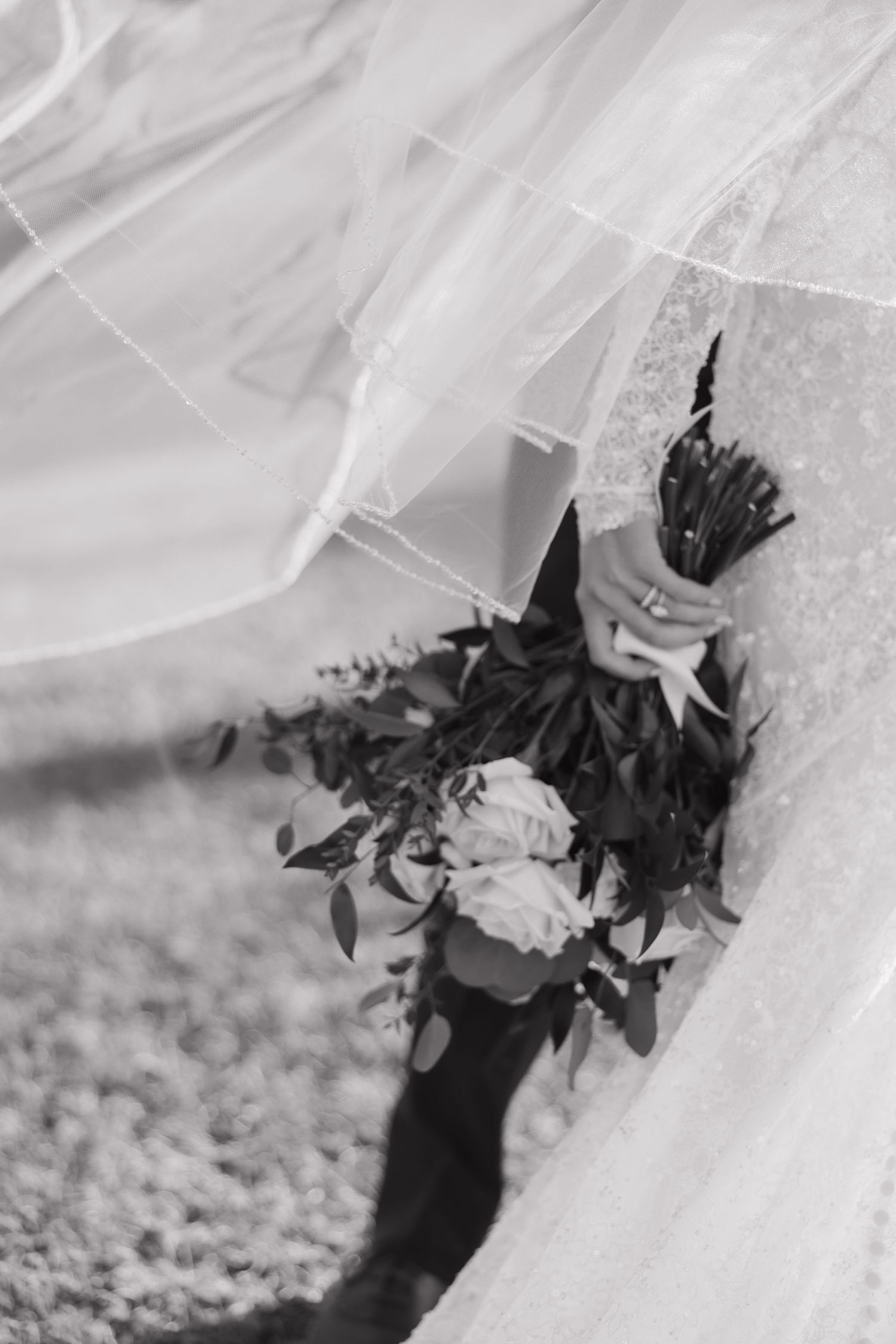 Black and white wedding detail photo showing delicate white veil fabric and floral accents creating an elegant composition.