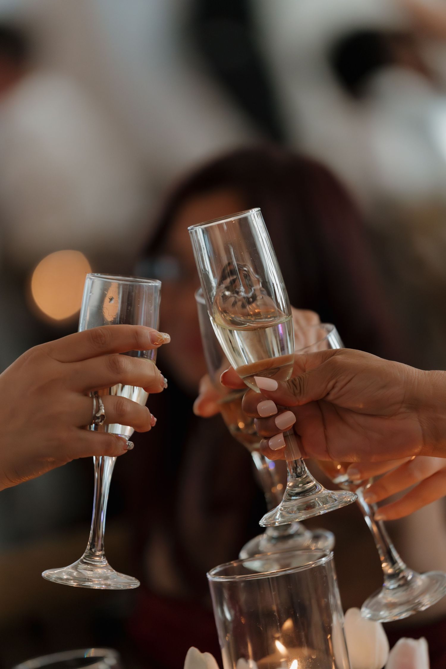 People toasting with elegant champagne flutes at a celebration event, with bokeh lights in the background.