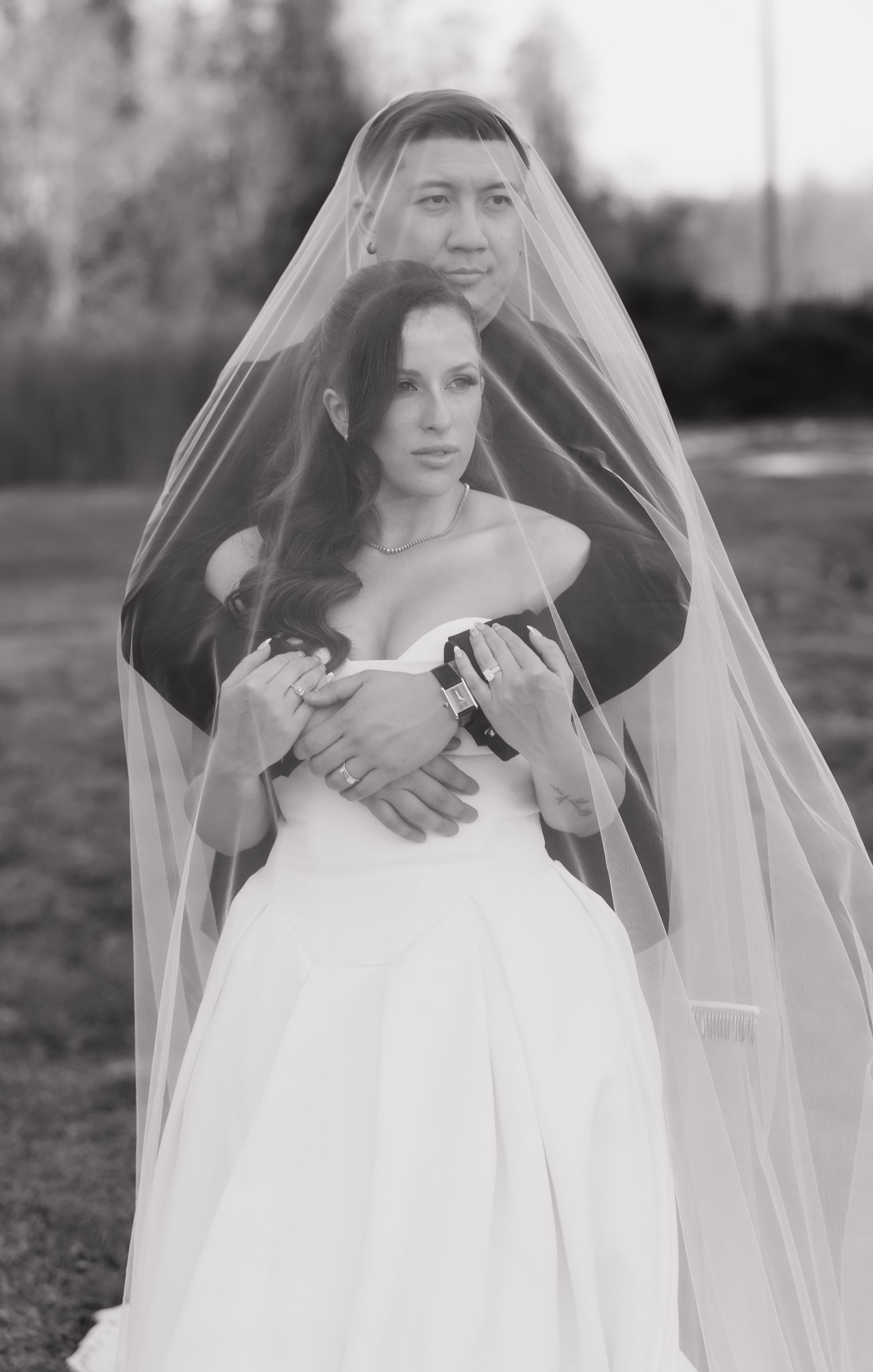 A black and white wedding portrait series showing a bride in a flowing white gown and veil in an outdoor setting.