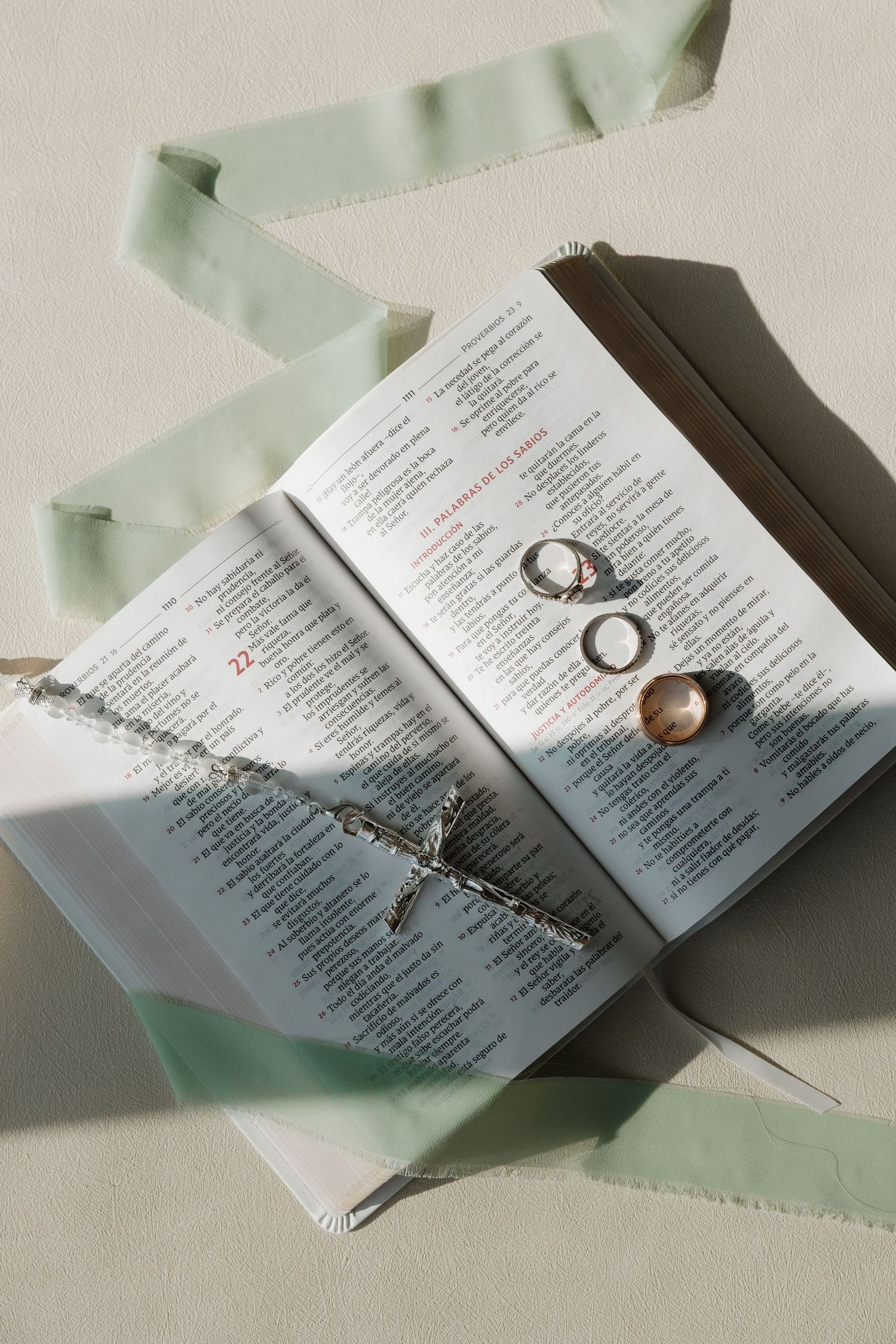 Wedding rings and program details artistically arranged on a light mint green background.