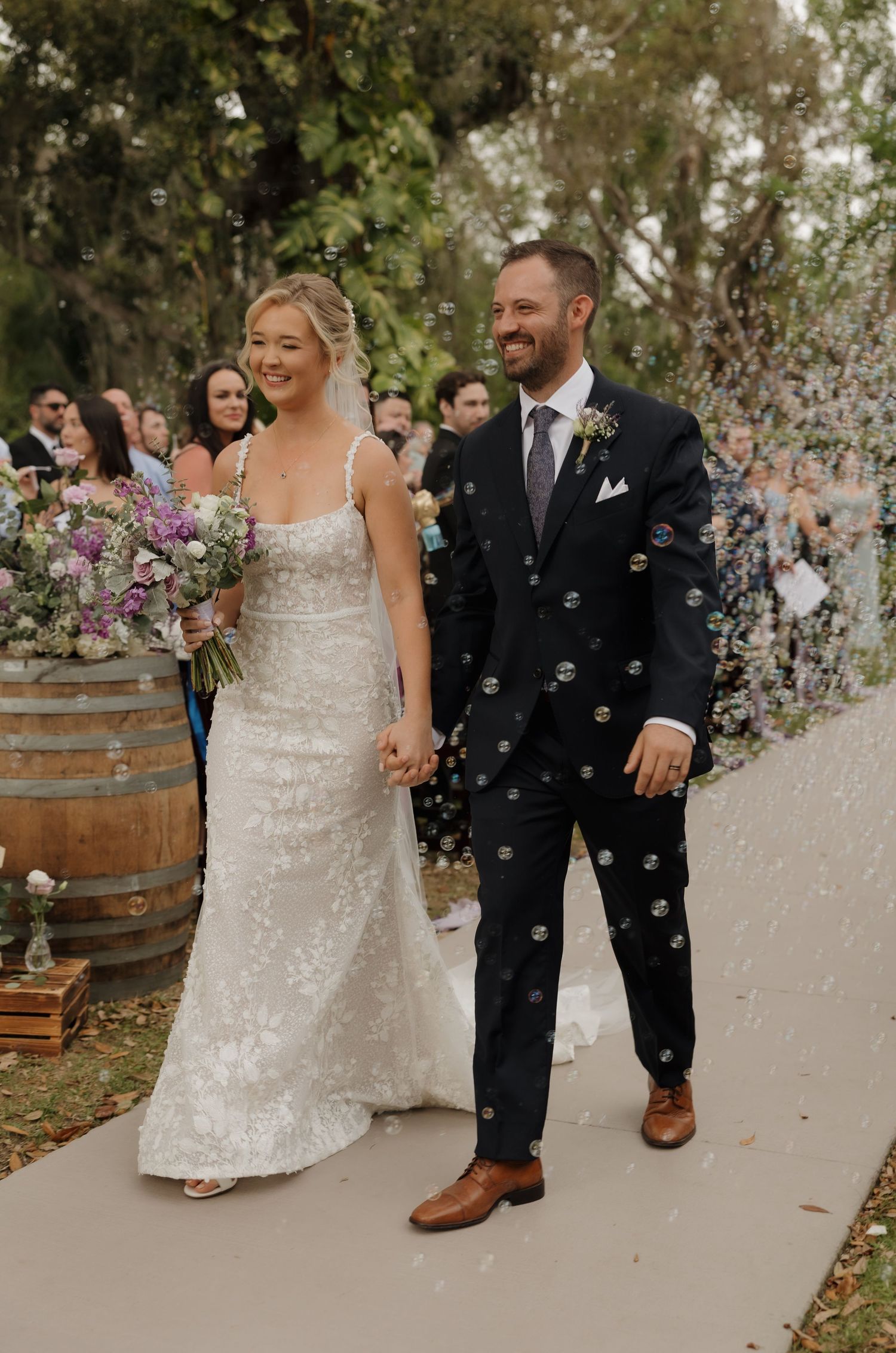 Happy newlyweds share joyful moments as bubbles float around them during outdoor wedding celebration.