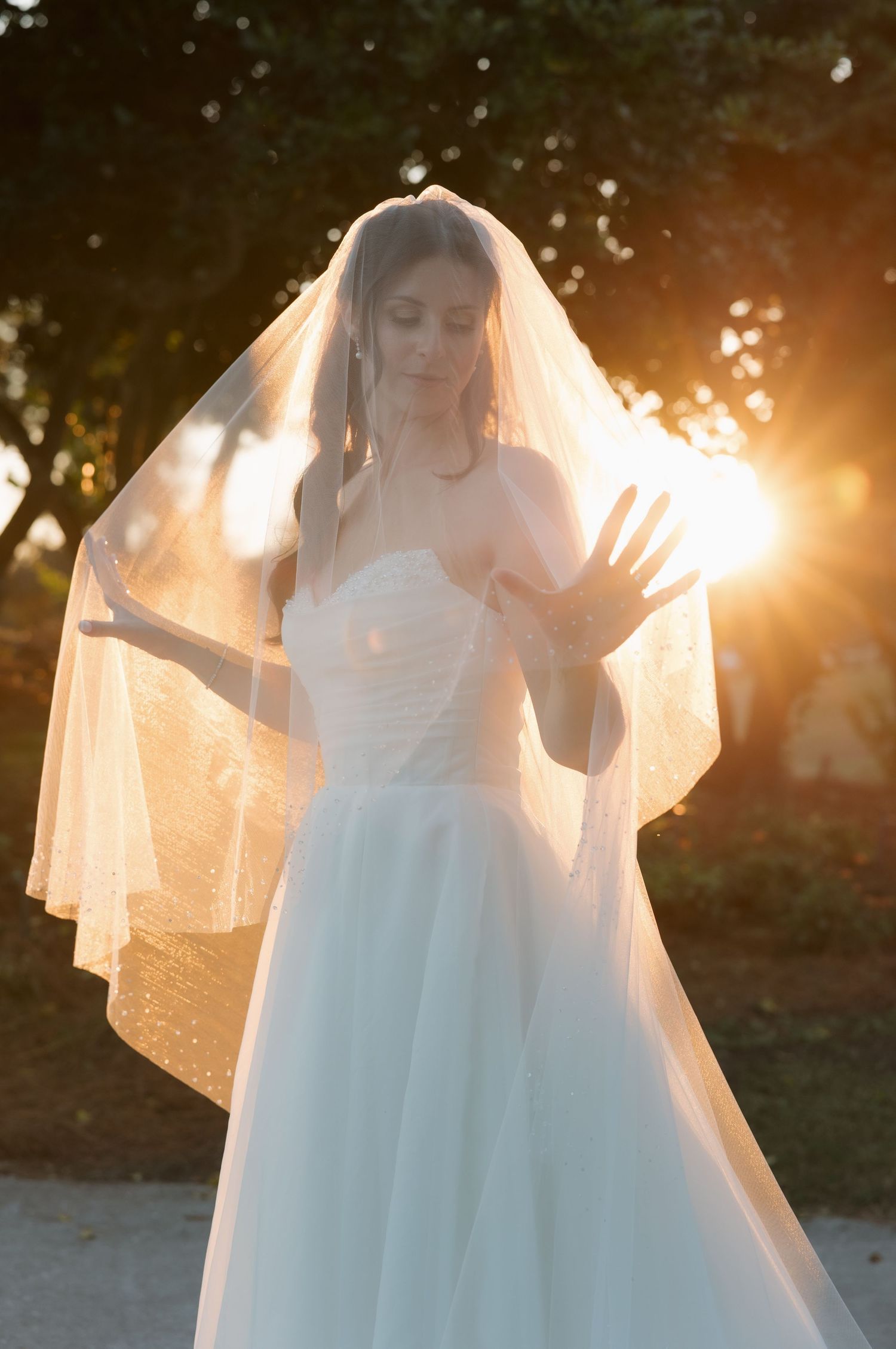 Ethereal bridal portrait with sunlit veil creating a dreamy golden glow during sunset.