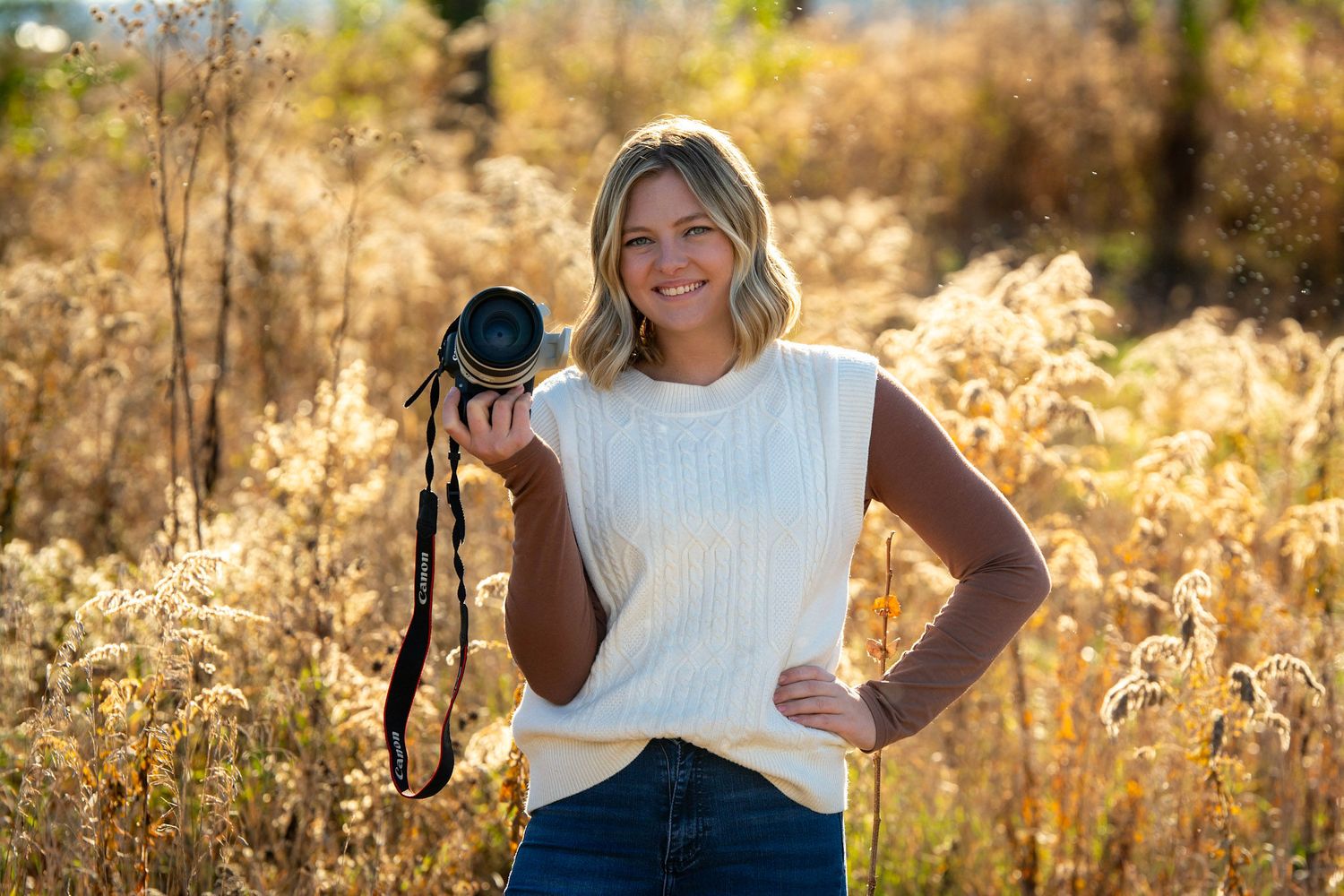 Outdoor photography session in a golden field during sunset with camera equipment visible.