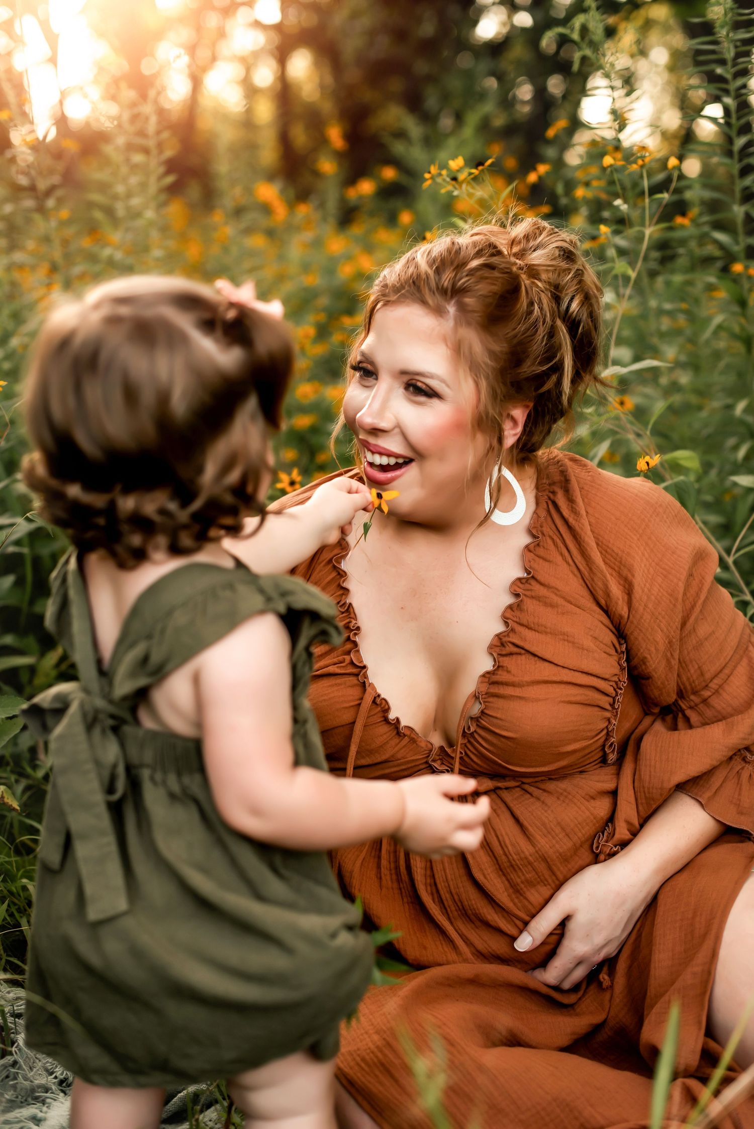 A tender moment captured in a rustic outdoor setting with warm lighting and wildflowers in the background.