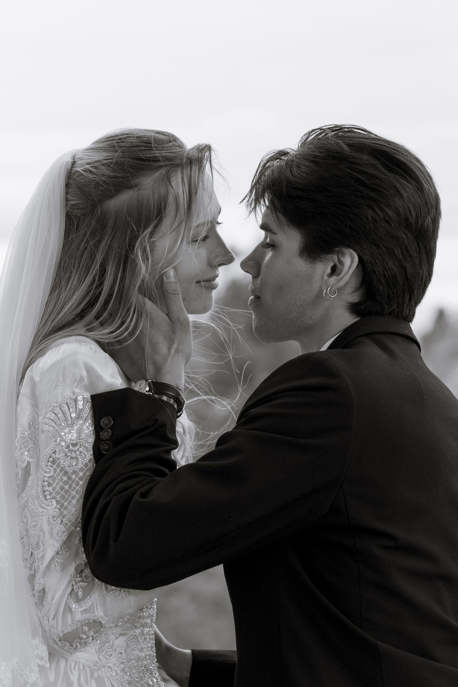 A romantic black and white wedding photo shows the bride in a lace dress and veil with her groom in a suit about to kiss.