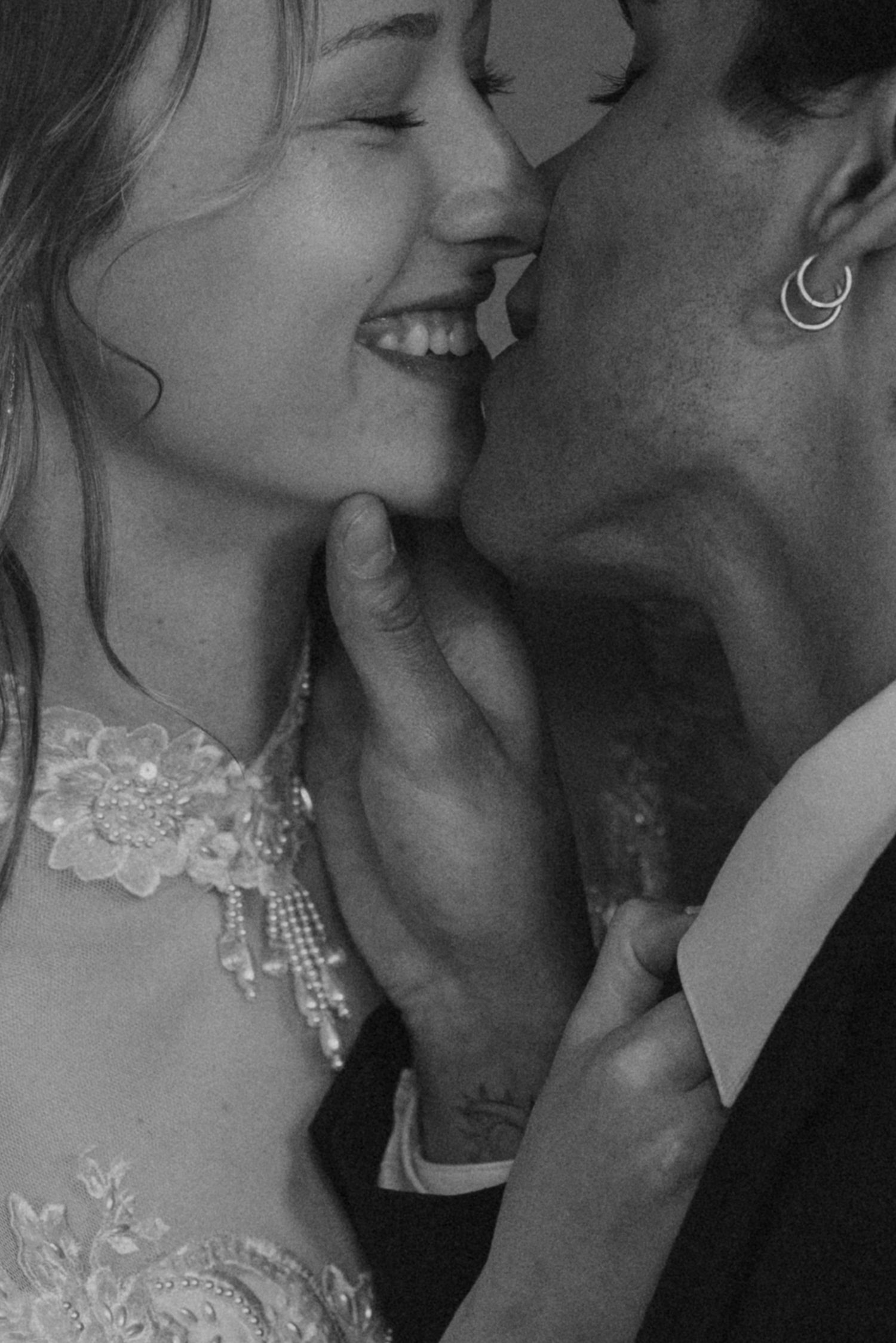 A romantic black and white wedding photograph showing an intimate joyful moment between a couple in bridal attire.
