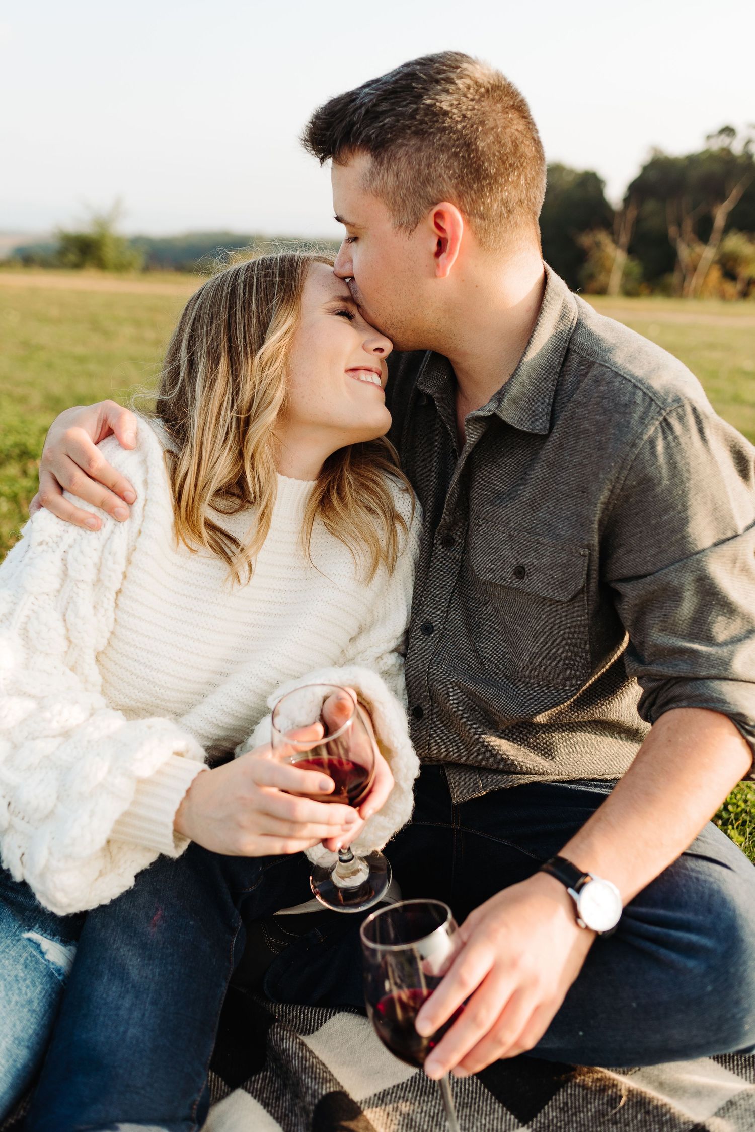 A couple shares an intimate moment while sitting outdoors holding wine glasses at sunset in Kutztown PA.