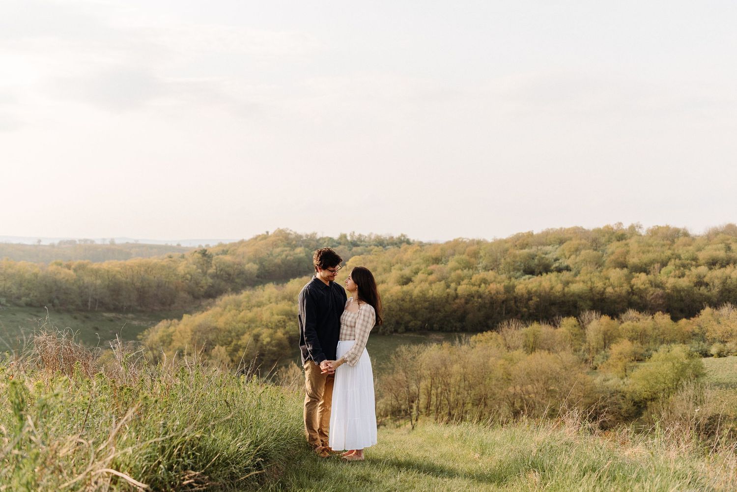 A couple walks together through a scenic hillside meadow at golden hour in Lehigh County PA.