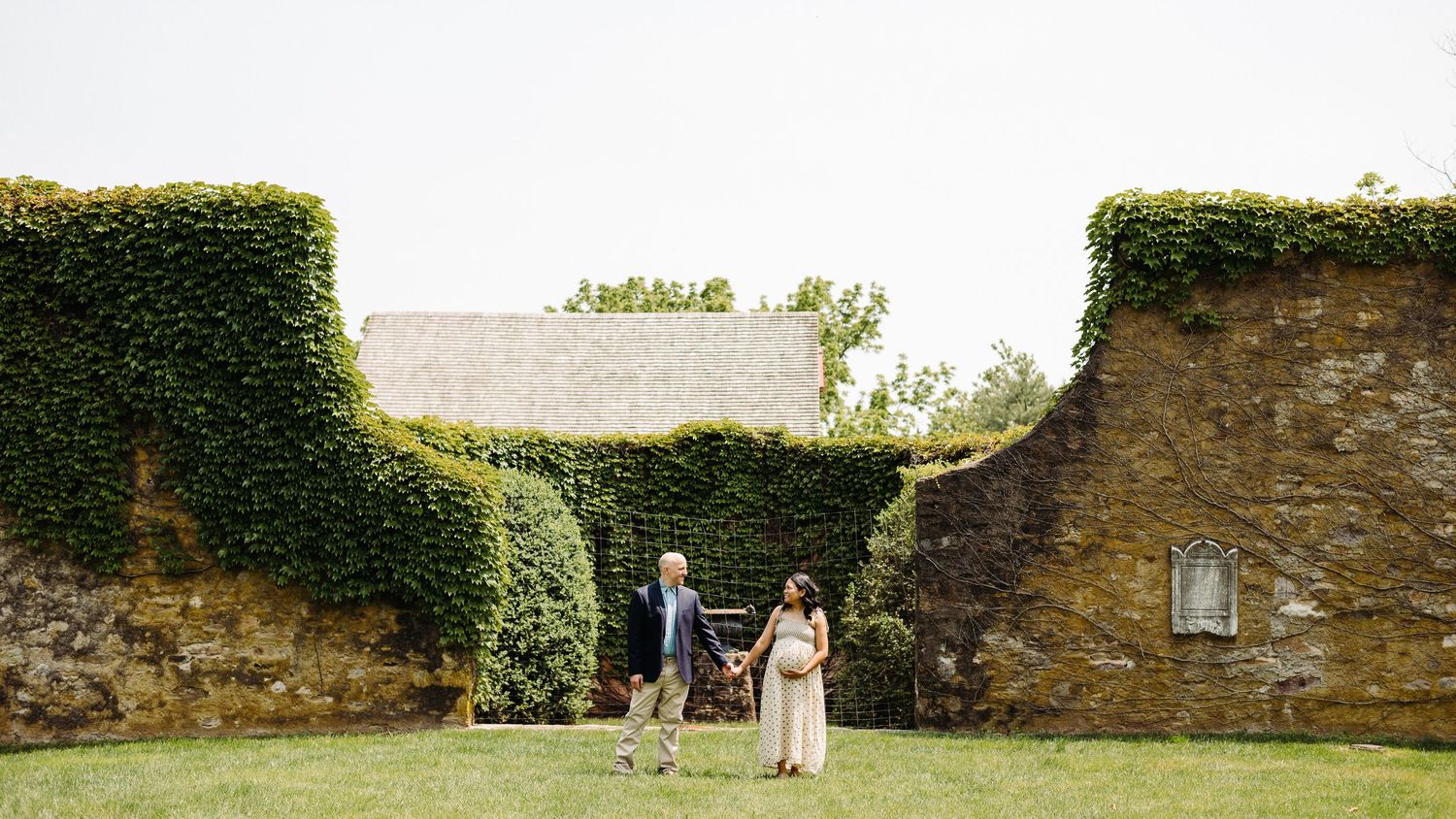 A panoramic view of a stone wall garden with lush green ivy and a pathway leading through the scenic landscape.