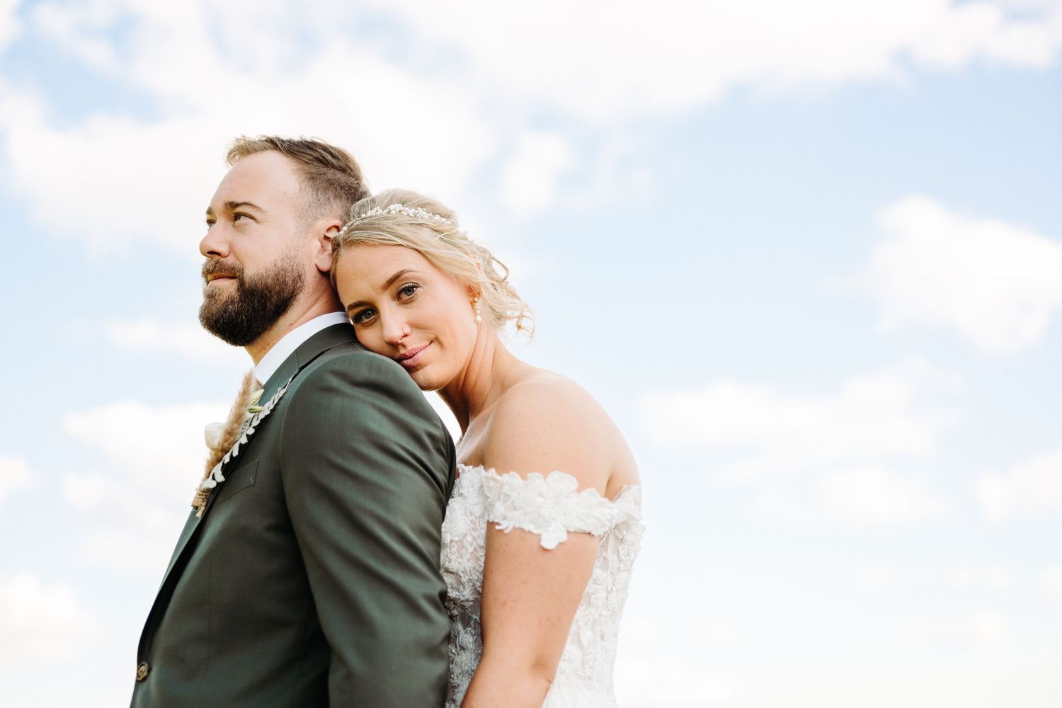 A romantic wedding couple embraces against a bright blue sky on their special day in Berks County PA.