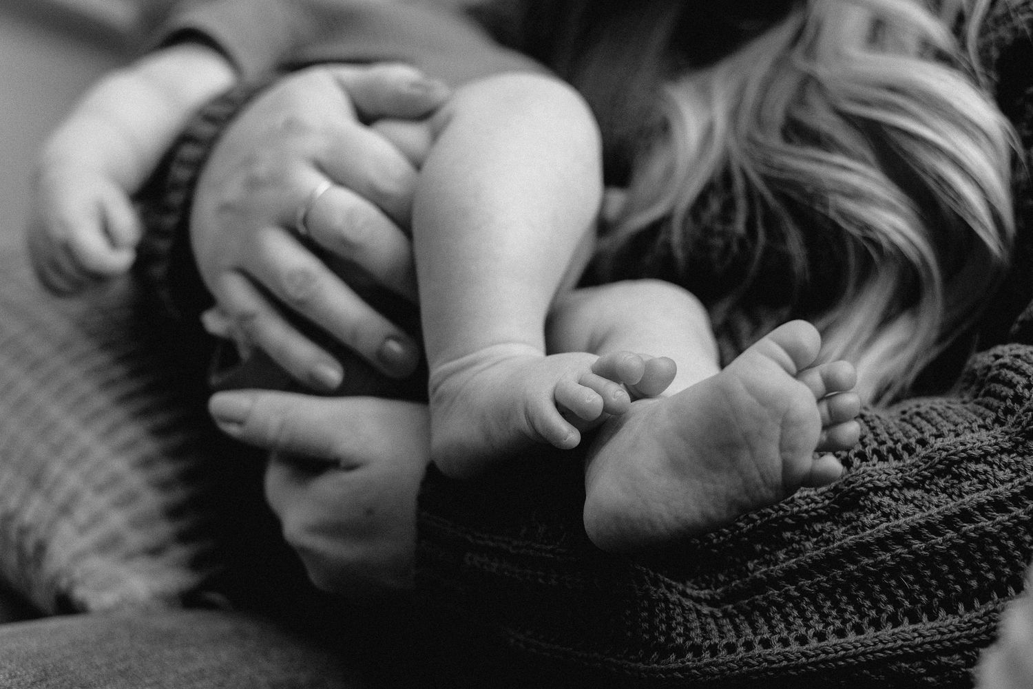 A black and white photo series showing close-up details of tender moments between parent and baby.