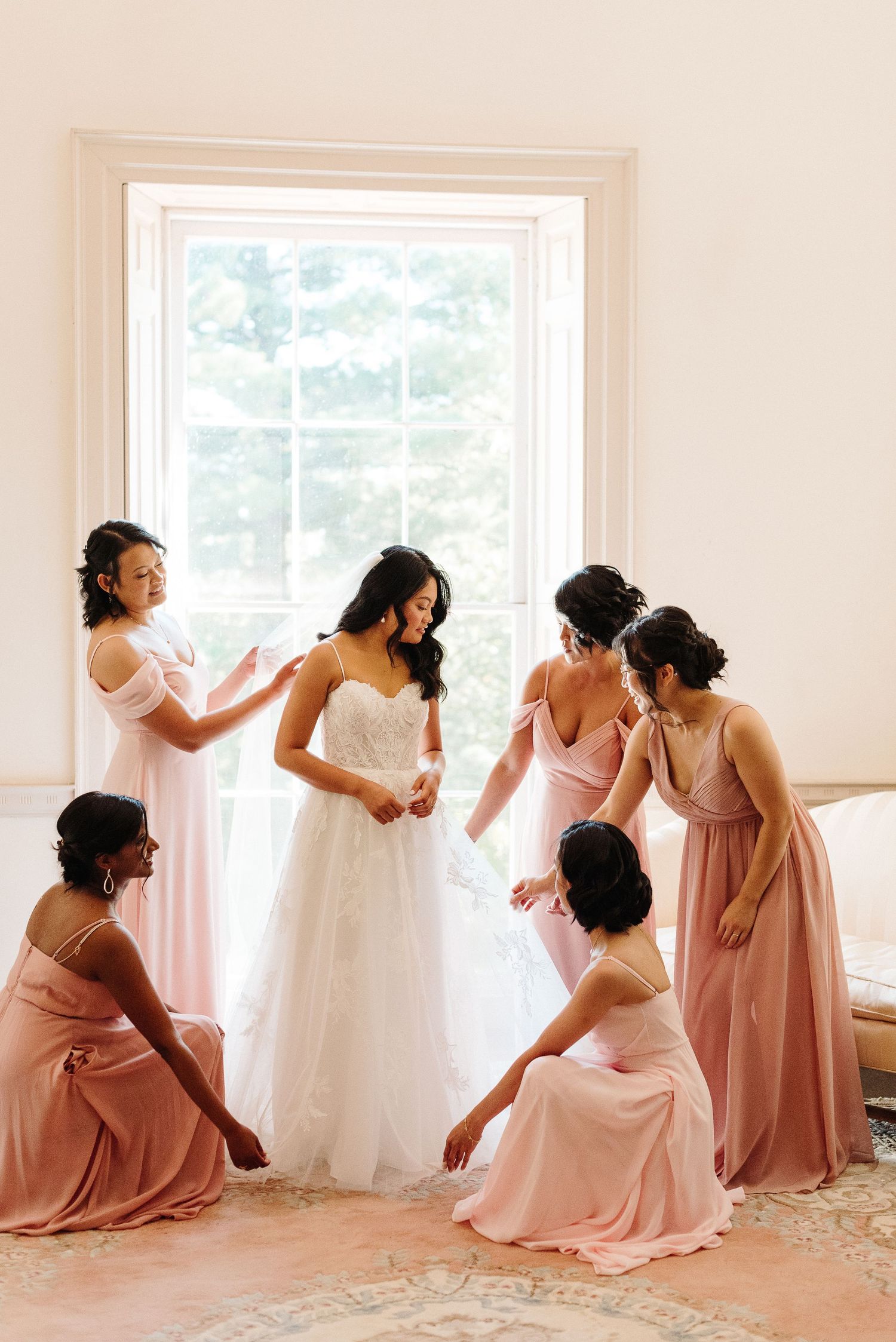 A sequence of photos showing bridesmaids in pink dresses helping with wedding preparations in a bright sunlit room.