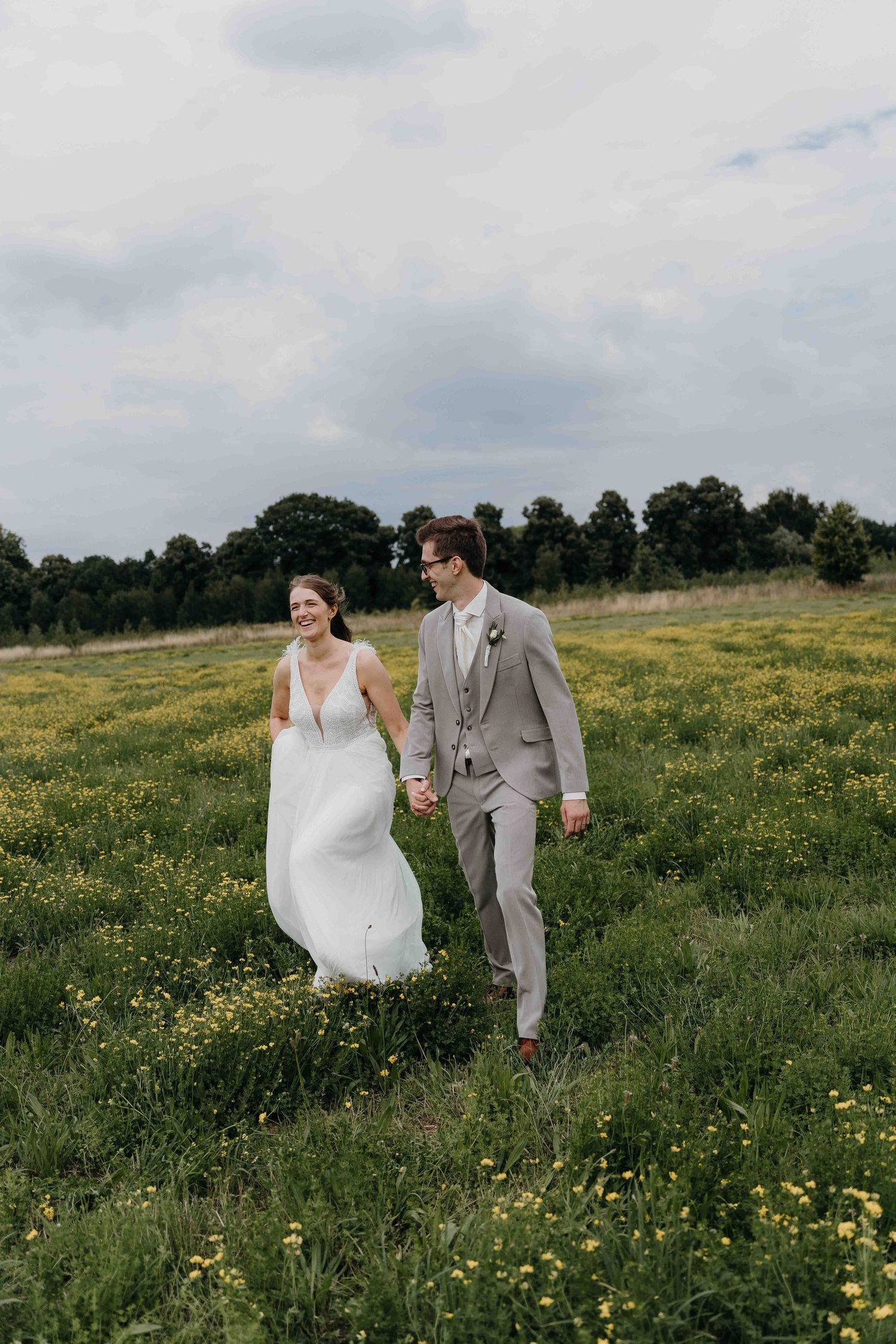 koppelfoto huwelijksshoot in gras met gele bloemetjes in Boechout