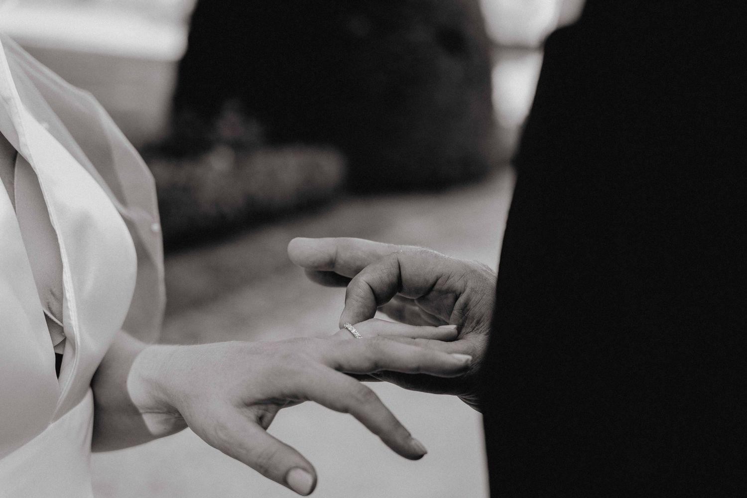 zwart wit foto van detailfoto koppel dat ringen aan elkaars hand schuift van huwelijksfotograaf en videograaf based in Antwerpen.