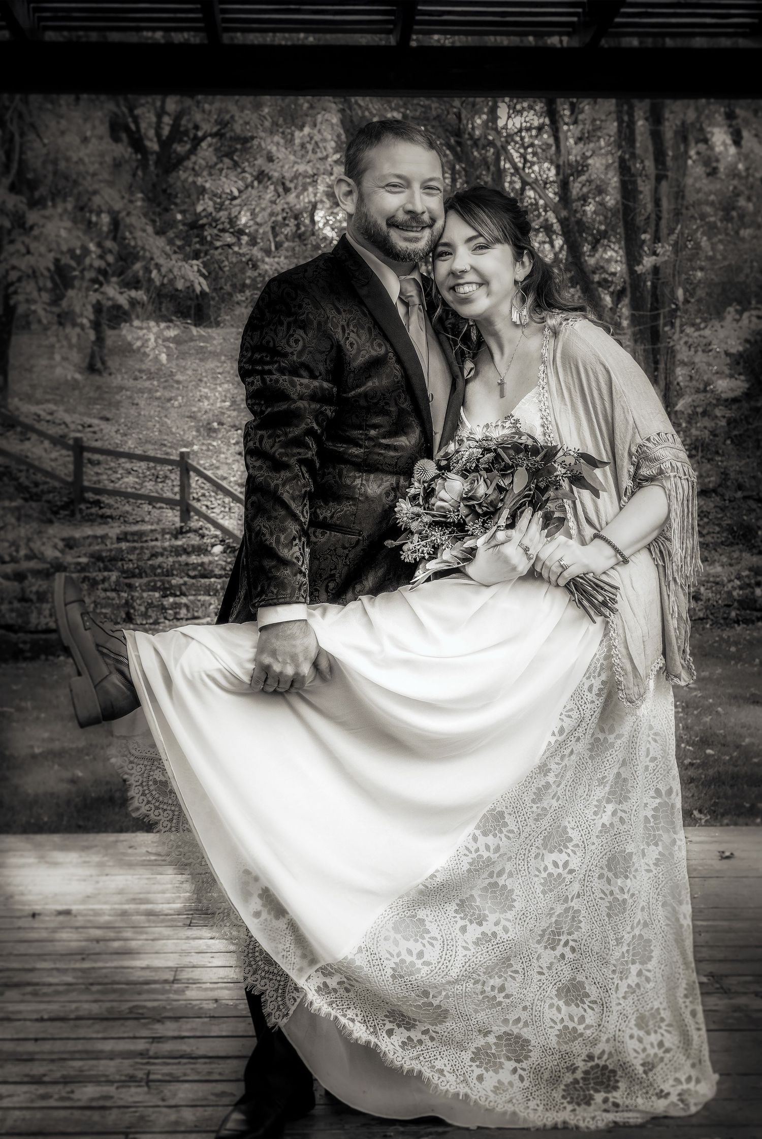 Happy bride and groom posing together in black and white wedding portrait outdoors.