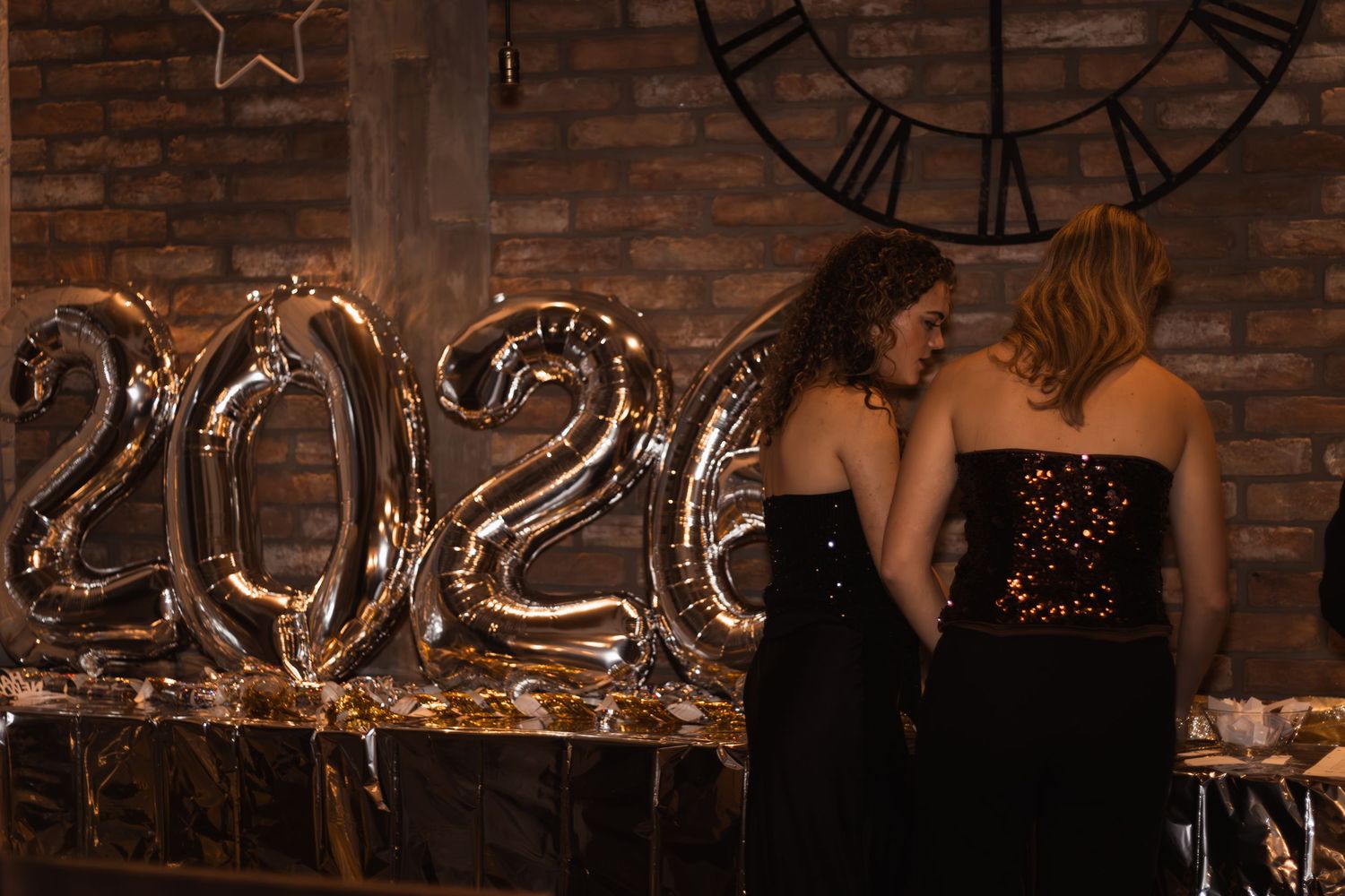 két nő fekete ruhában pózol 2026-os lufik mellett